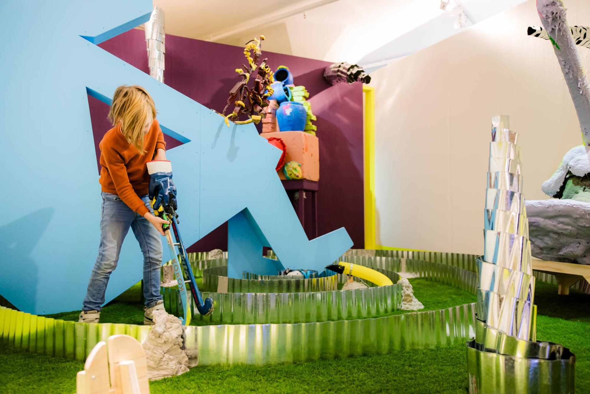 Kind speelt met hockeystick in tentoonstelling. 