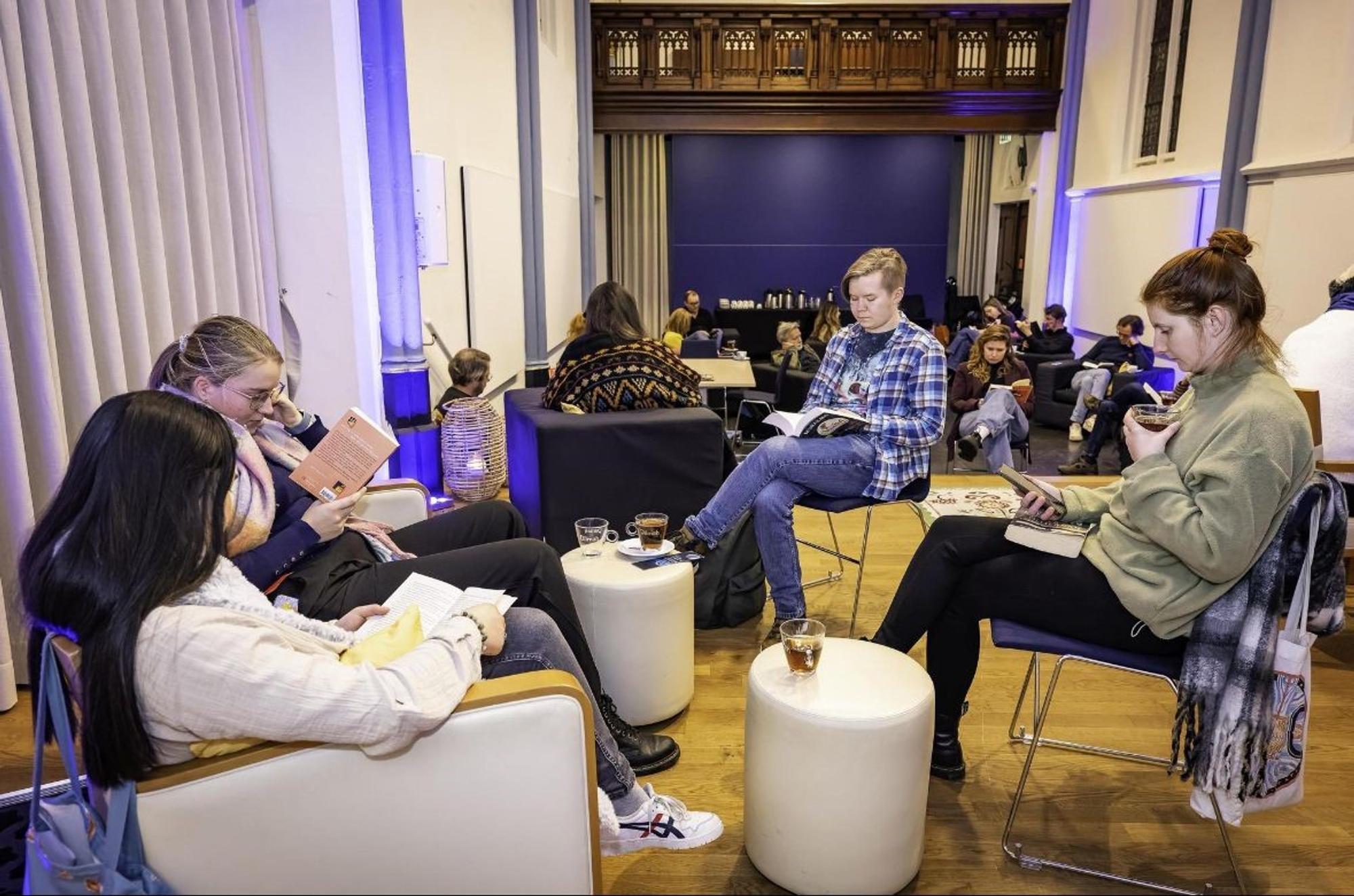 Groep mensen leest in stilte in een modern verlichte ruimte met blauwe sfeerverlichting