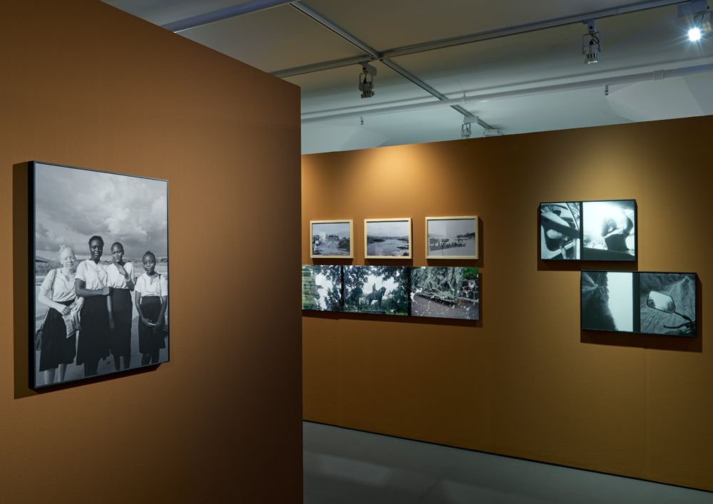 Twee bruine wanden in het museum waar verschillende zwart-witfoto's hangen.