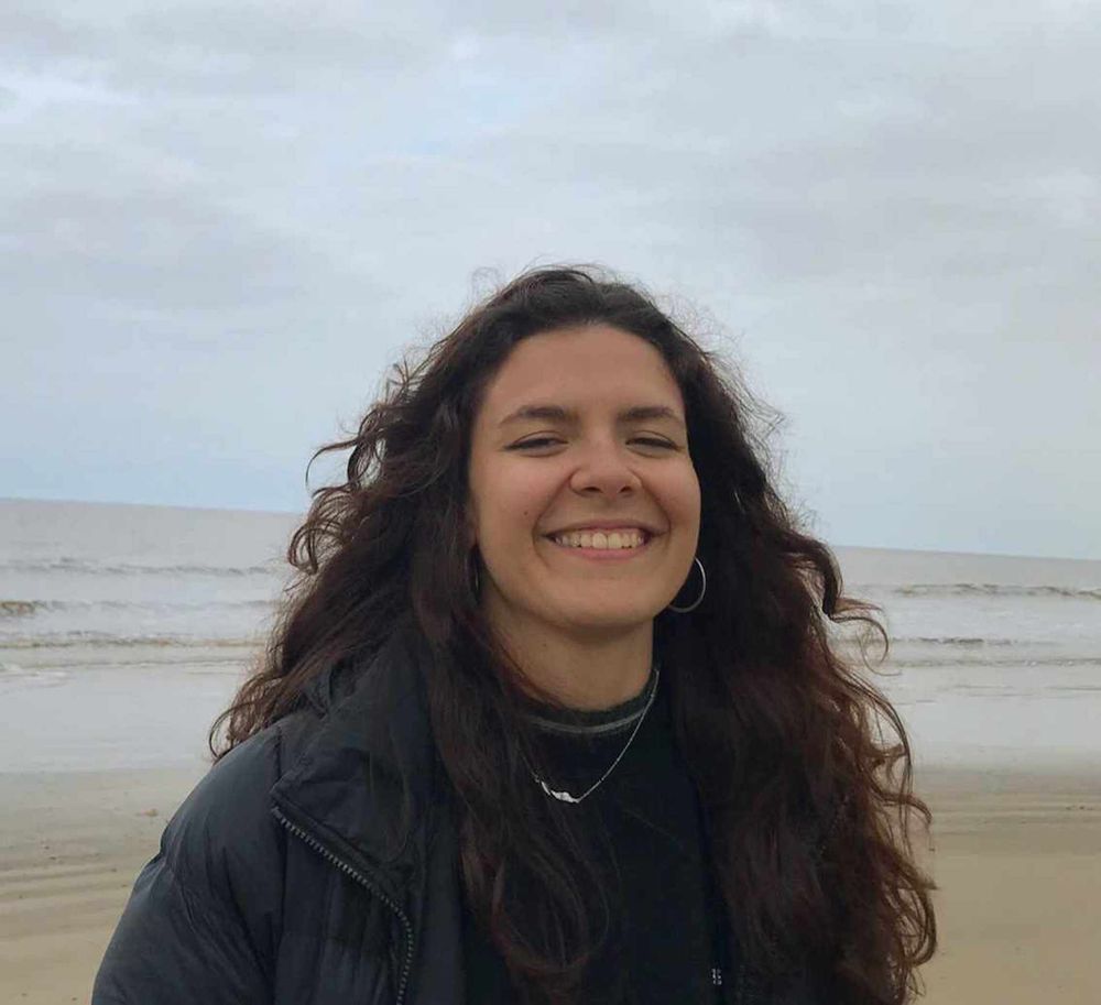 Foto van lachende Mikayla Vieira Riberio, met op het achtergrond het strand en de zee