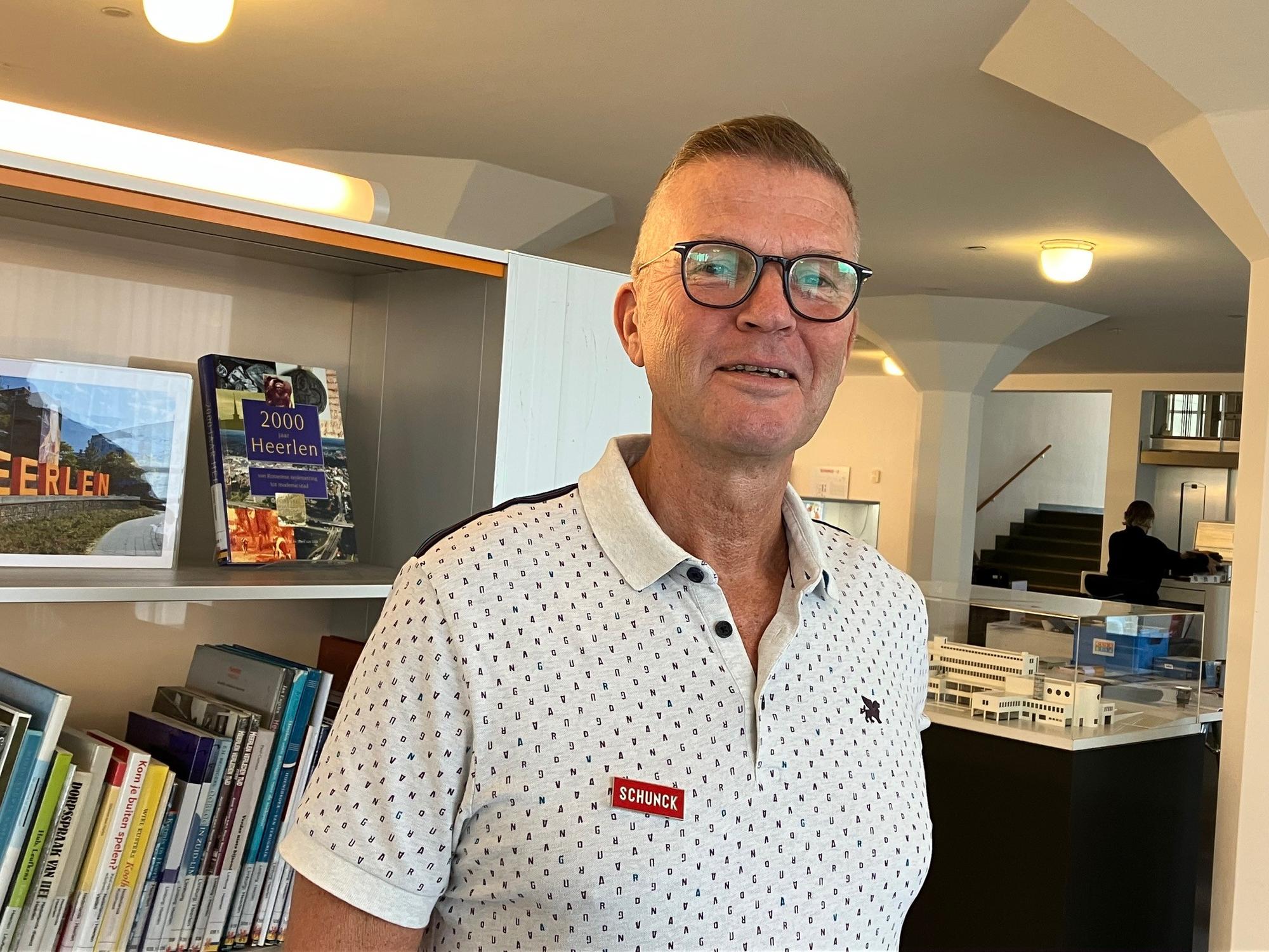 Portret vrijwilliger Ed Meurs Bibliotheek Taalhuis met boeken kast en maquette van Schunck op de achtergrond. 