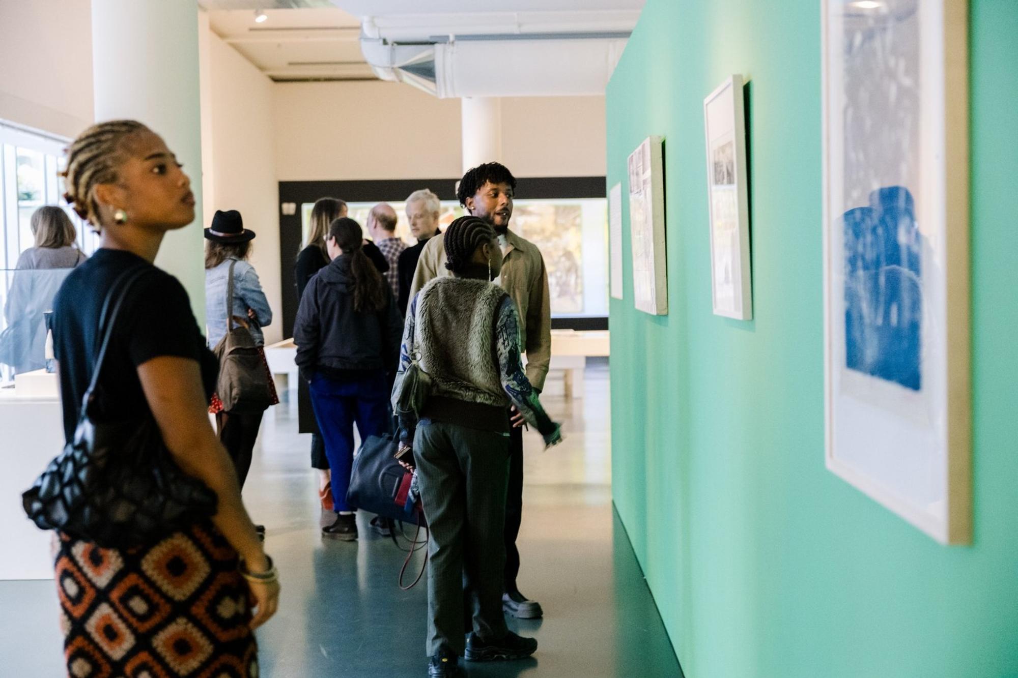 Bezoekers verkennen de tentoonstelling Rinella Alfonso & Charles Eyck: Aan de andere kant van de oceaan in de museumzaal van SCHUNCK.