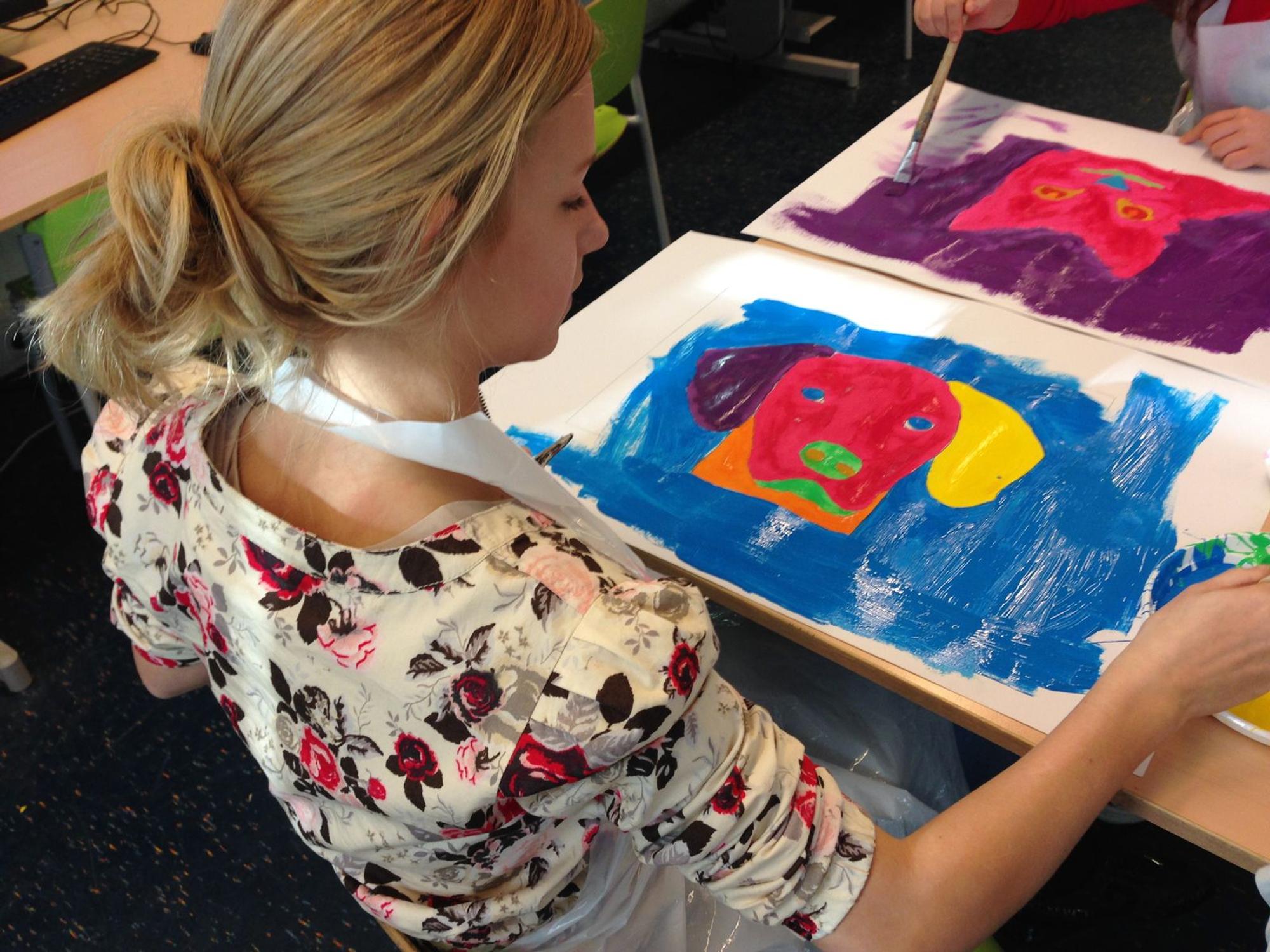 Een tiener schildert een kleurrijk portret van een hond tijdens een creatieve workshop, geïnspireerd op popart-stijlen.