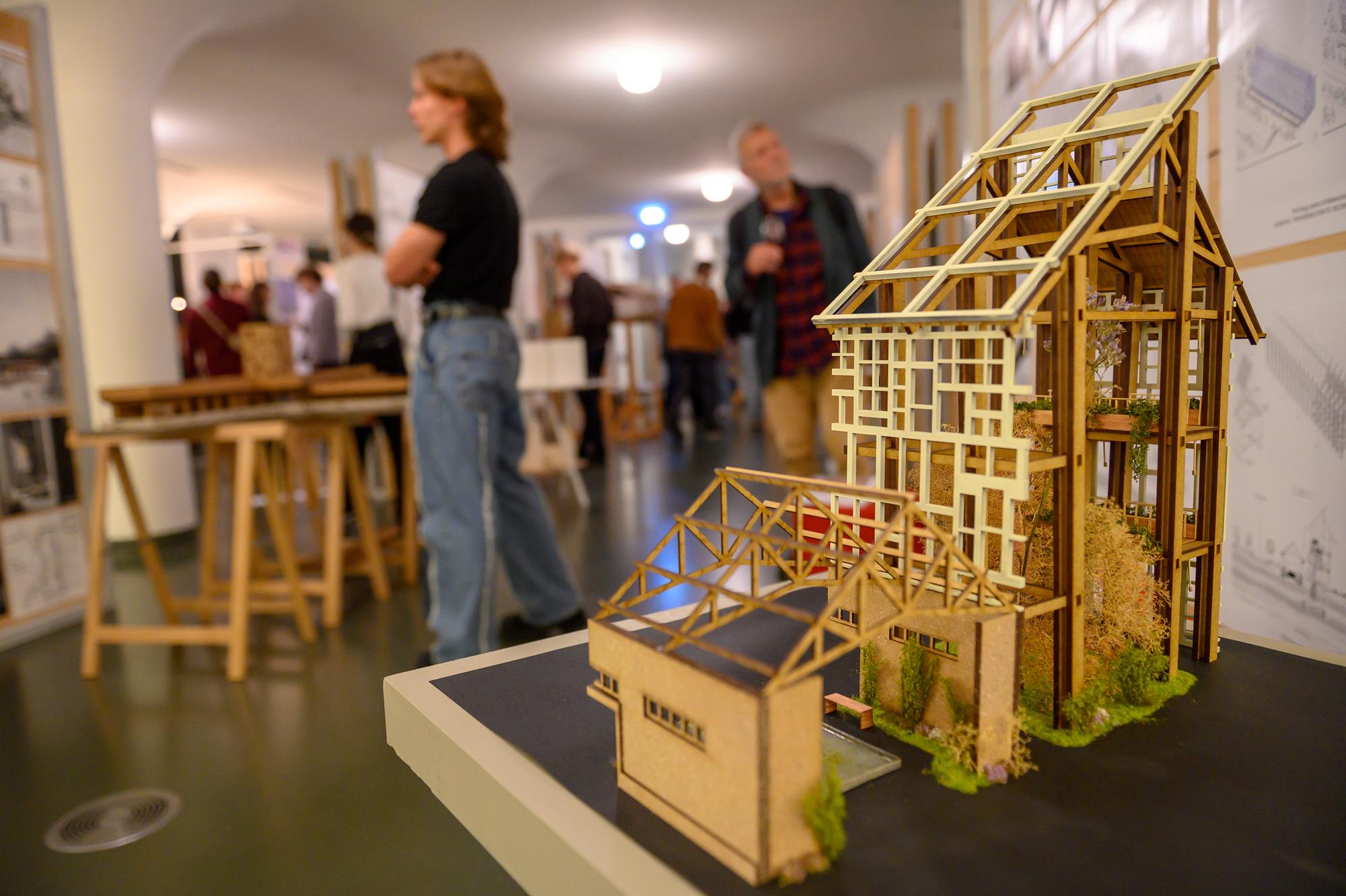 Maquette met in de achtergrond bezoekers die kijken naar architectuurtentoonstelling. 