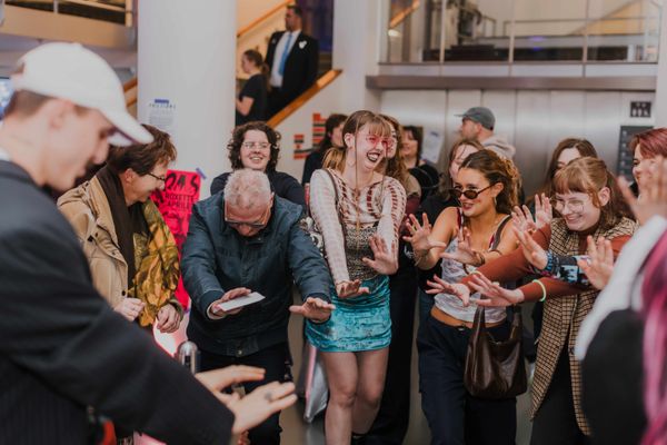 Bezoekers dansen samen met hun handen voor zich in de lucht. 