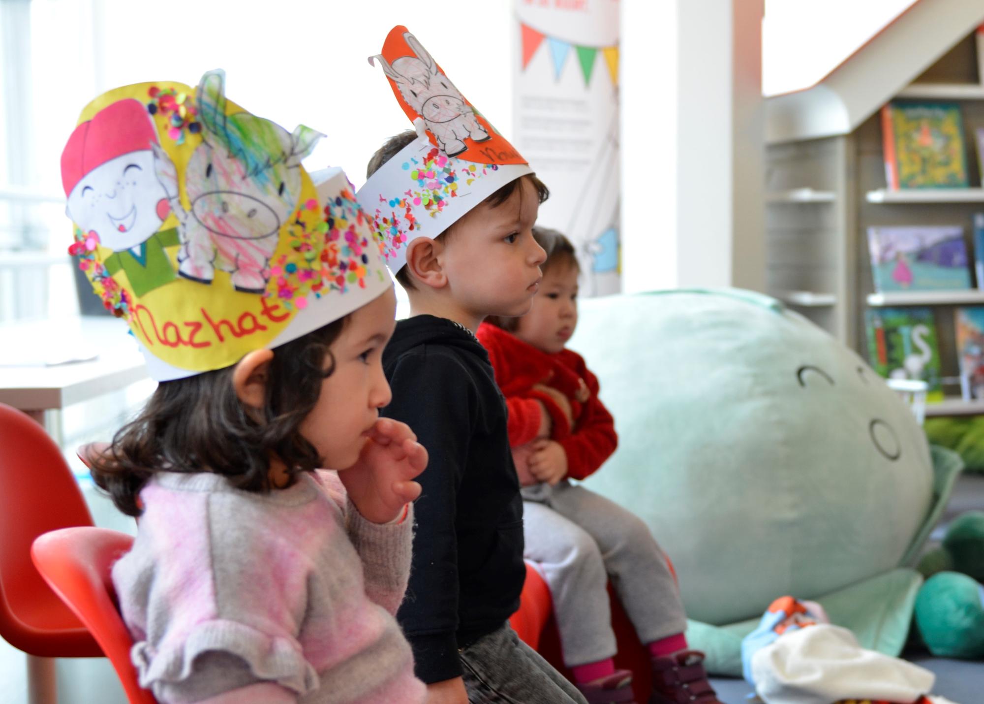 Kinderen met geknutselde kronen zitten in een kring. 