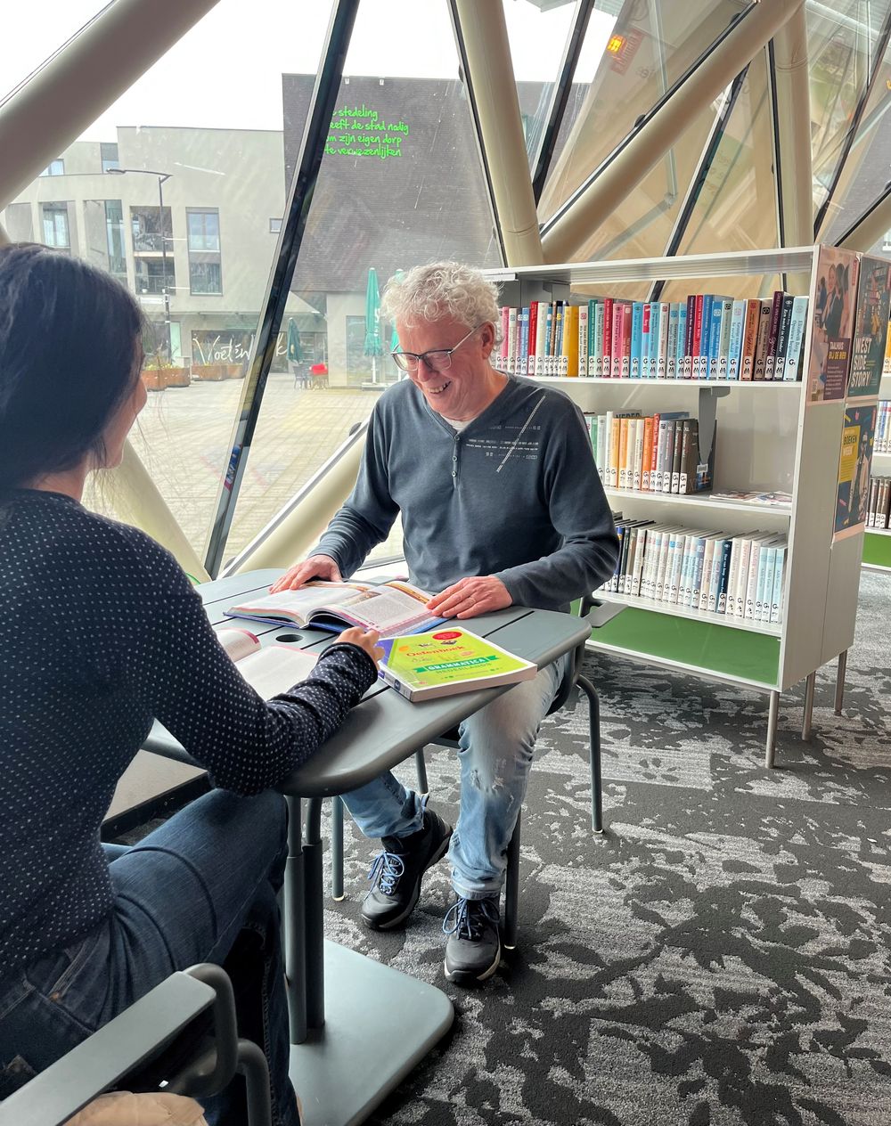 Vrijwilliger Ger Hanno zit aan tafel met boek. 