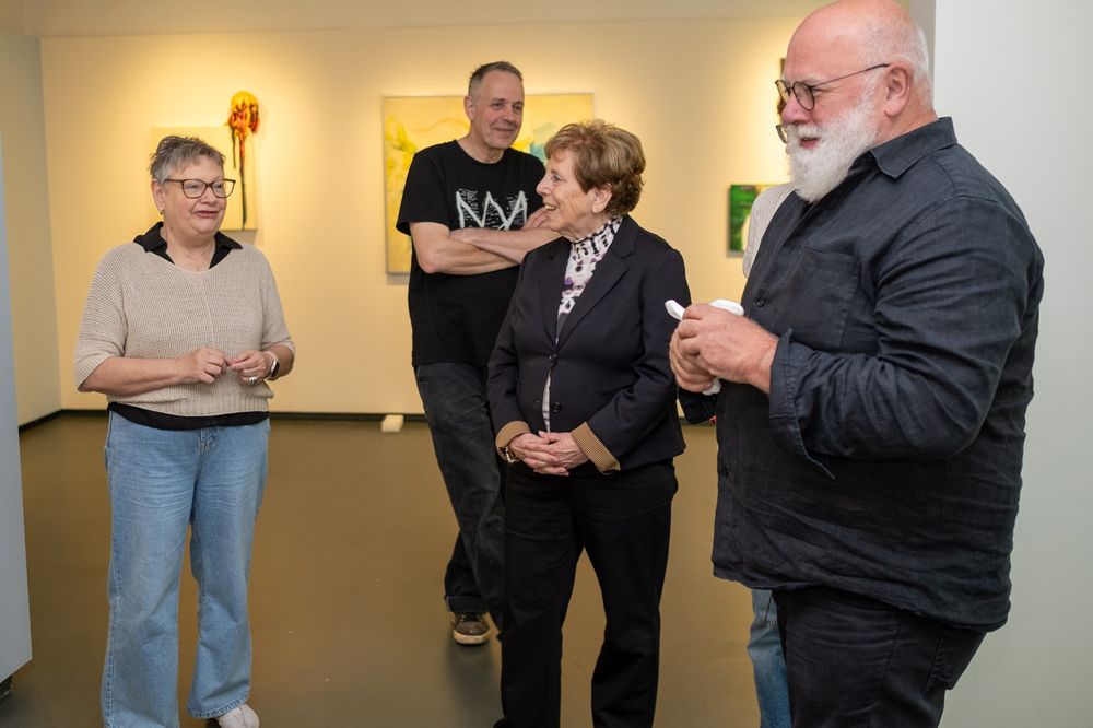 Een groepje mensen staat met elkaar in gesprek en kijkt aandachtig naar elkaar, terwijl ze zich verdiepen in het gesprek.
