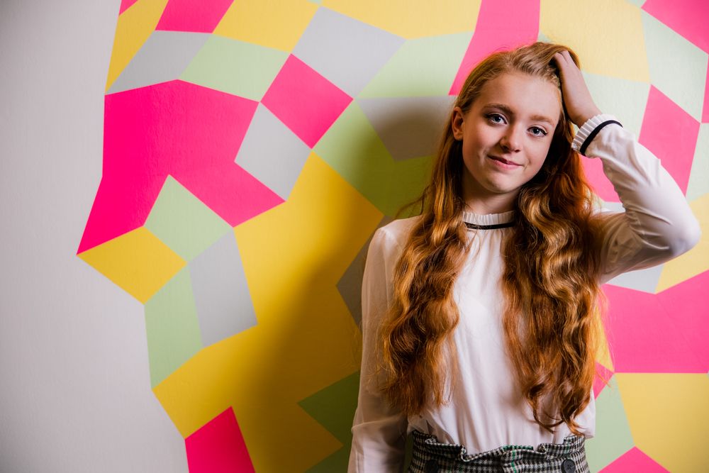 Portret van een jonge vrouw voor een kleurrijke muurschildering.