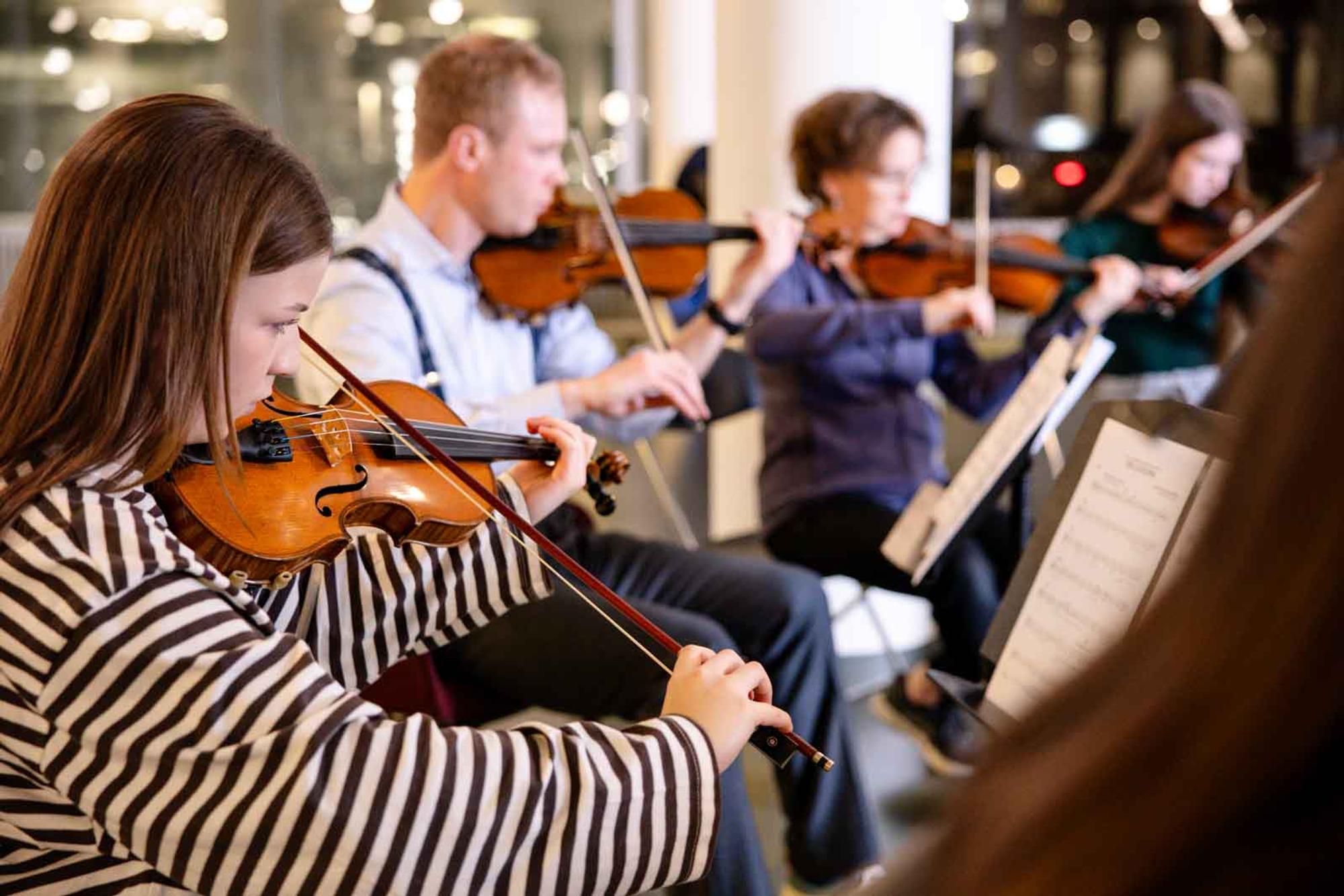 Een groepsfoto van mensen in een orkest die violen bespelen.
