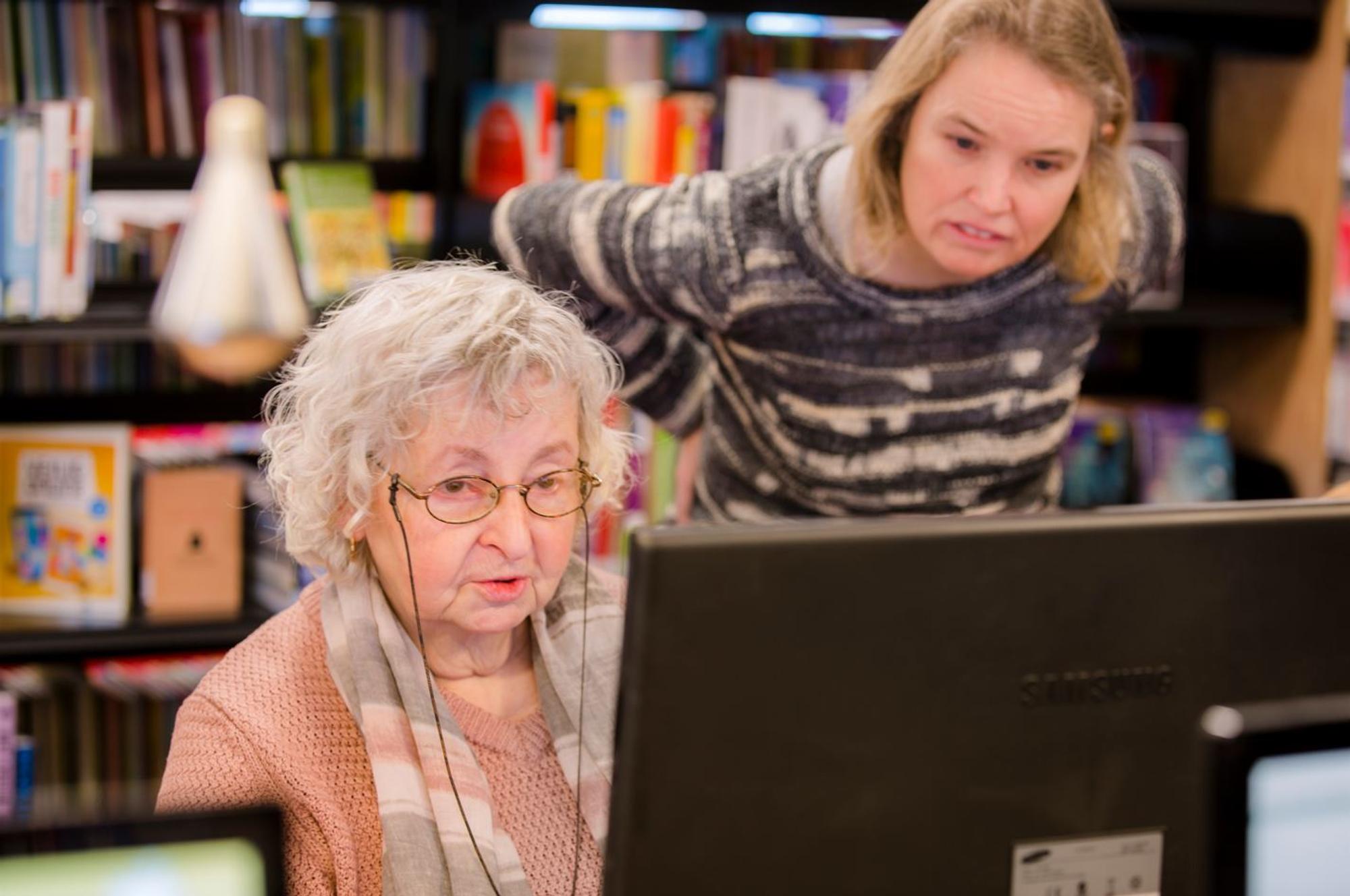 Twee vrouwen achter computerscherm in de bibliotheek. 