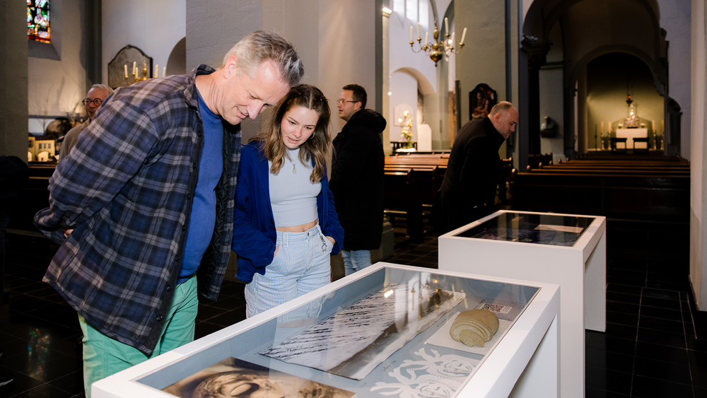 Bezoekers kijken in vitrines naar objecten in de Pancratiuskerk.