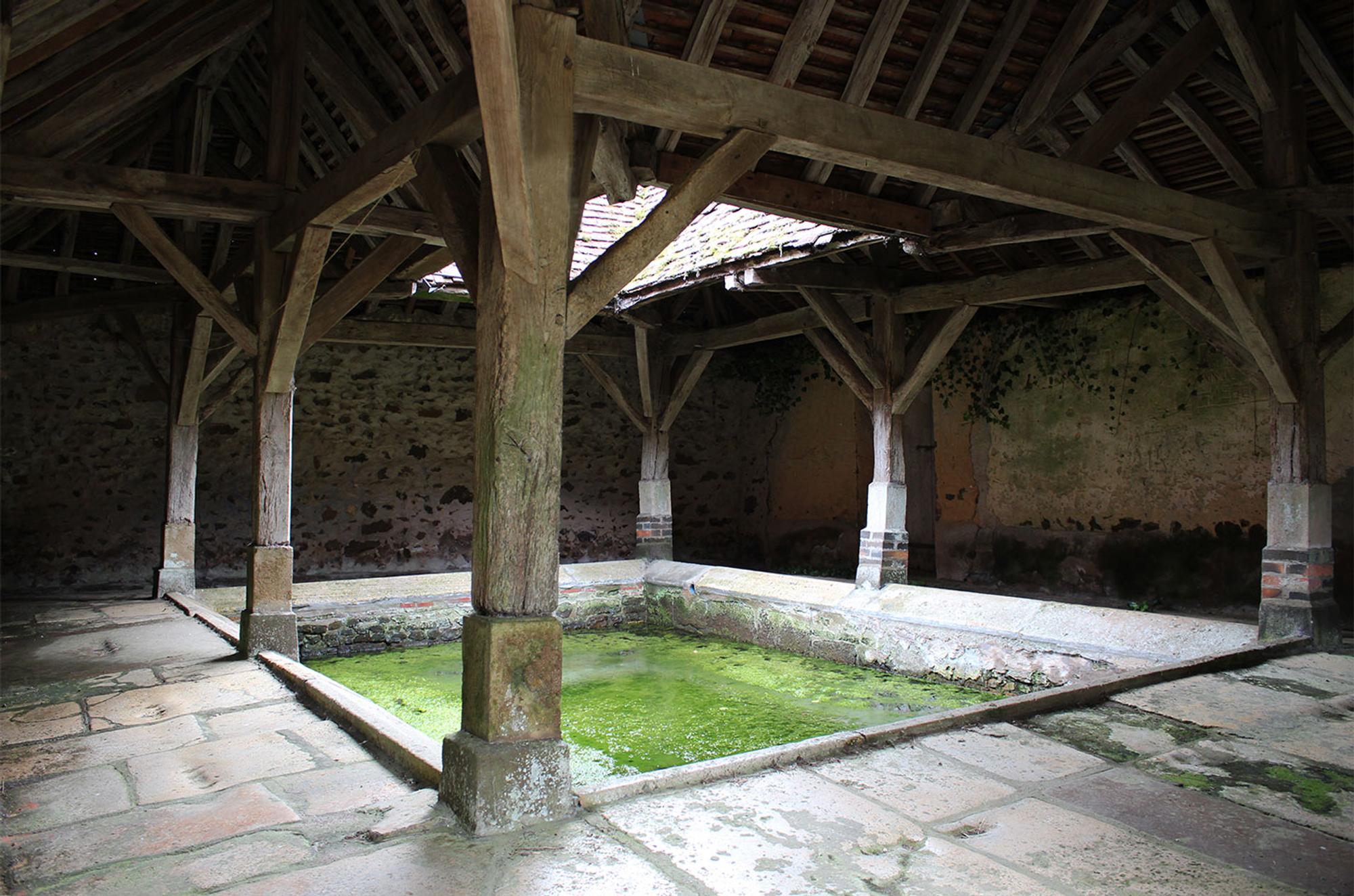 Historisch washuis met houten houtconstructie en waterbassin, locatie van het project van kunstenaar Charlotte Koenen.