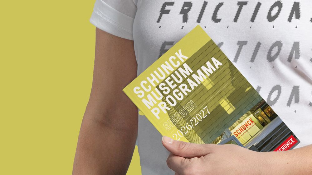 Persoon houdt een folder vast van het SCHUNCK Museumprogramma 2026/2027 met een gele omslag.