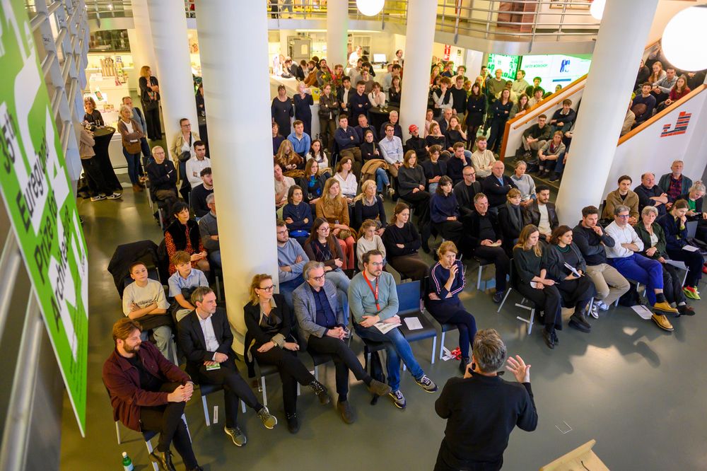 Publiek luistert aandachtig naar een spreker tijdens de openingsceremonie van de Euregional Architecture Prize 2026 in het atrium van SCHUNCK.