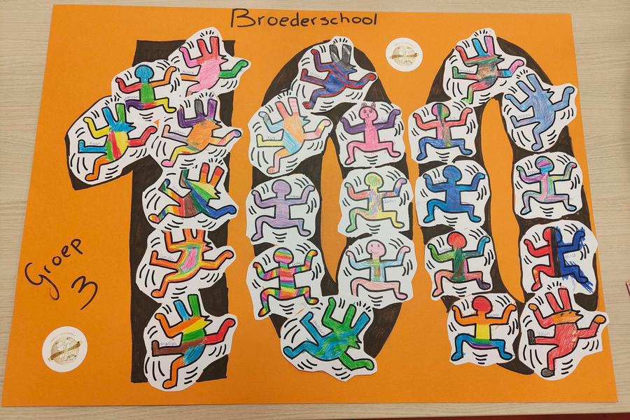 Grote oranje poster met het cijfer 100, gevuld met ingekleurde figuren in de stijl van Keith Haring, gemaakt door leerlingen van groep 3 van de Broederschool.
