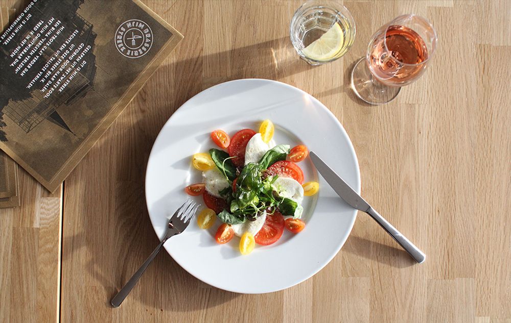 Bord met salade, een glas wijn en een glas water op tafel.