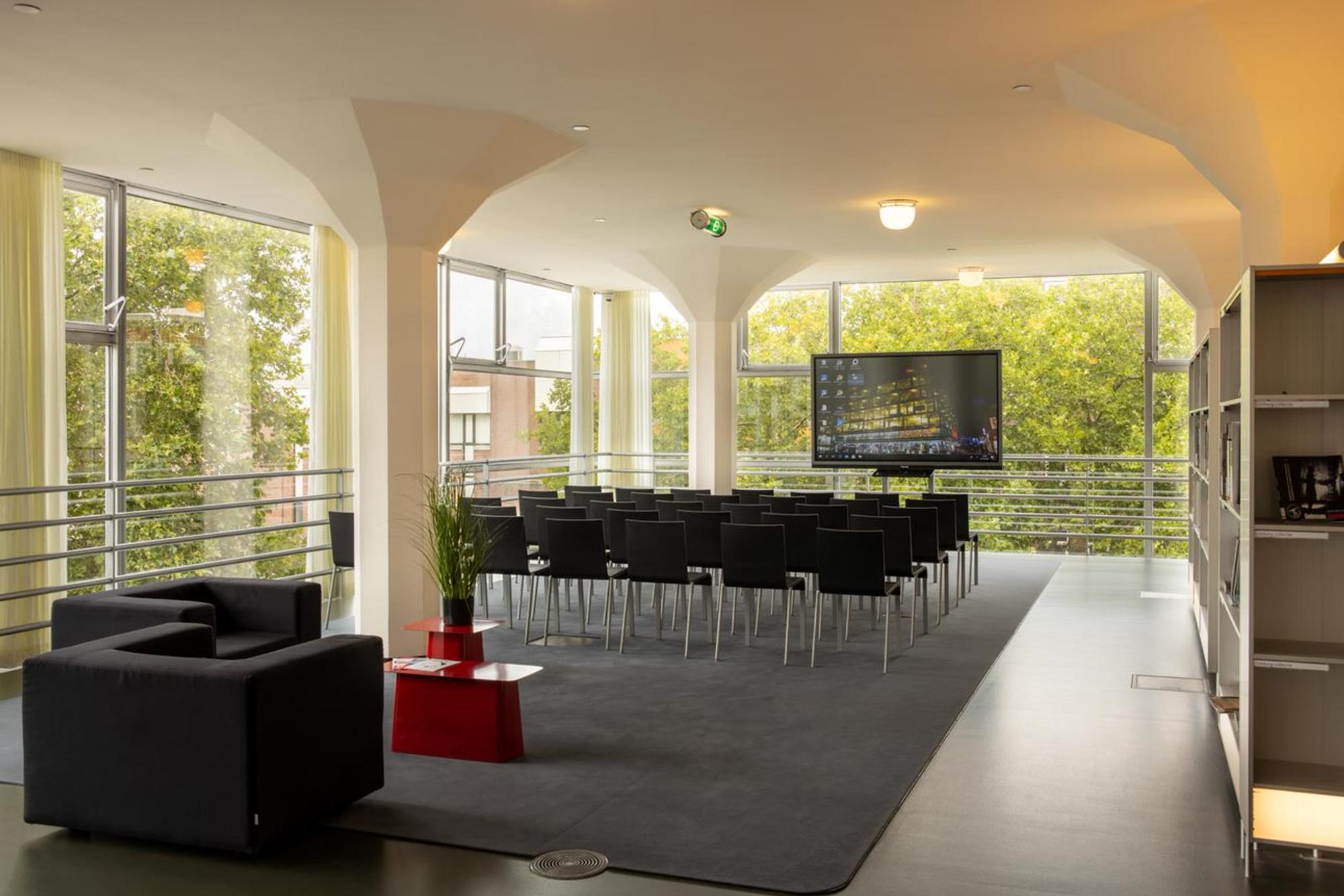 Presentatieruimte bij SCHUNCK, rijen stoelen voor een presentatiescherm. 