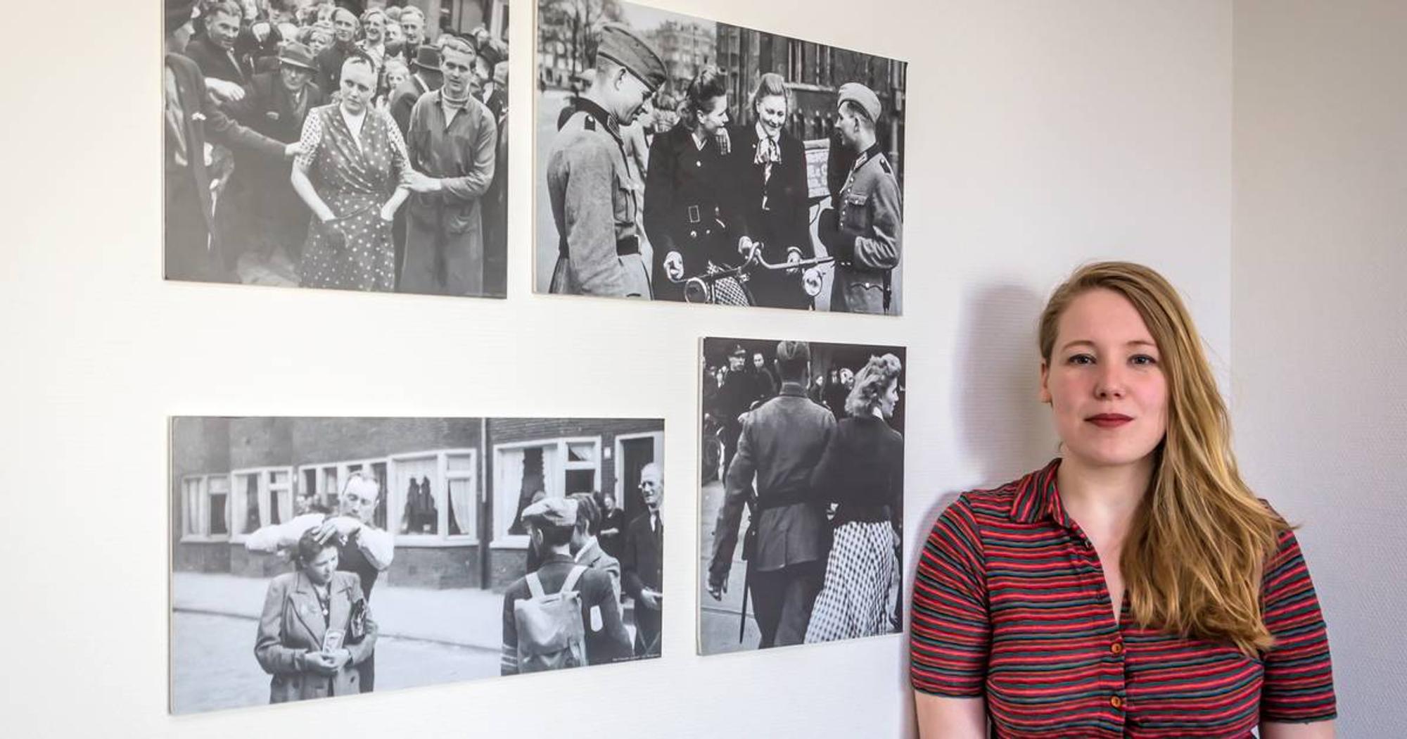 Rianne die voor een muur staat waarop verschillende zwart/wit foto's van vrouwen uit de tweede wereldoorlog gepresenteerd worden. 