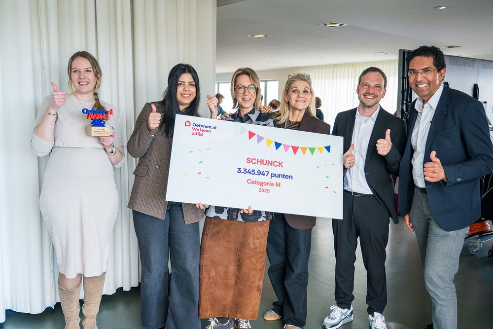 Zes personen staan in een lichte binnenruimte en houden een groot bord vast met daarop de tekst “SCHUNCK – 3.345.947 punten – Categorie M – 2025”. Een van hen houdt een trofee vast. Enkele personen steken een duim omhoog.