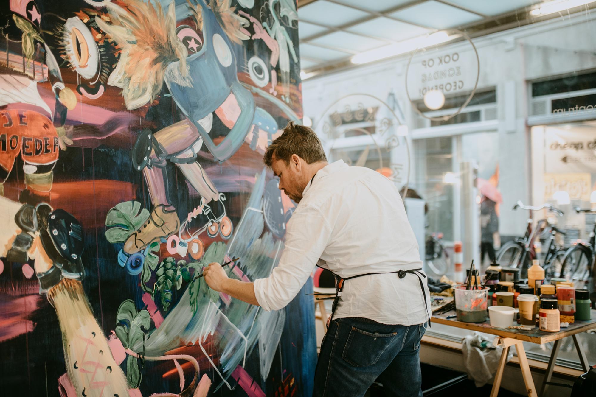 Kunstenaar David Bade schildert een groot schilderij in de centrale hal van SCHUNCK.