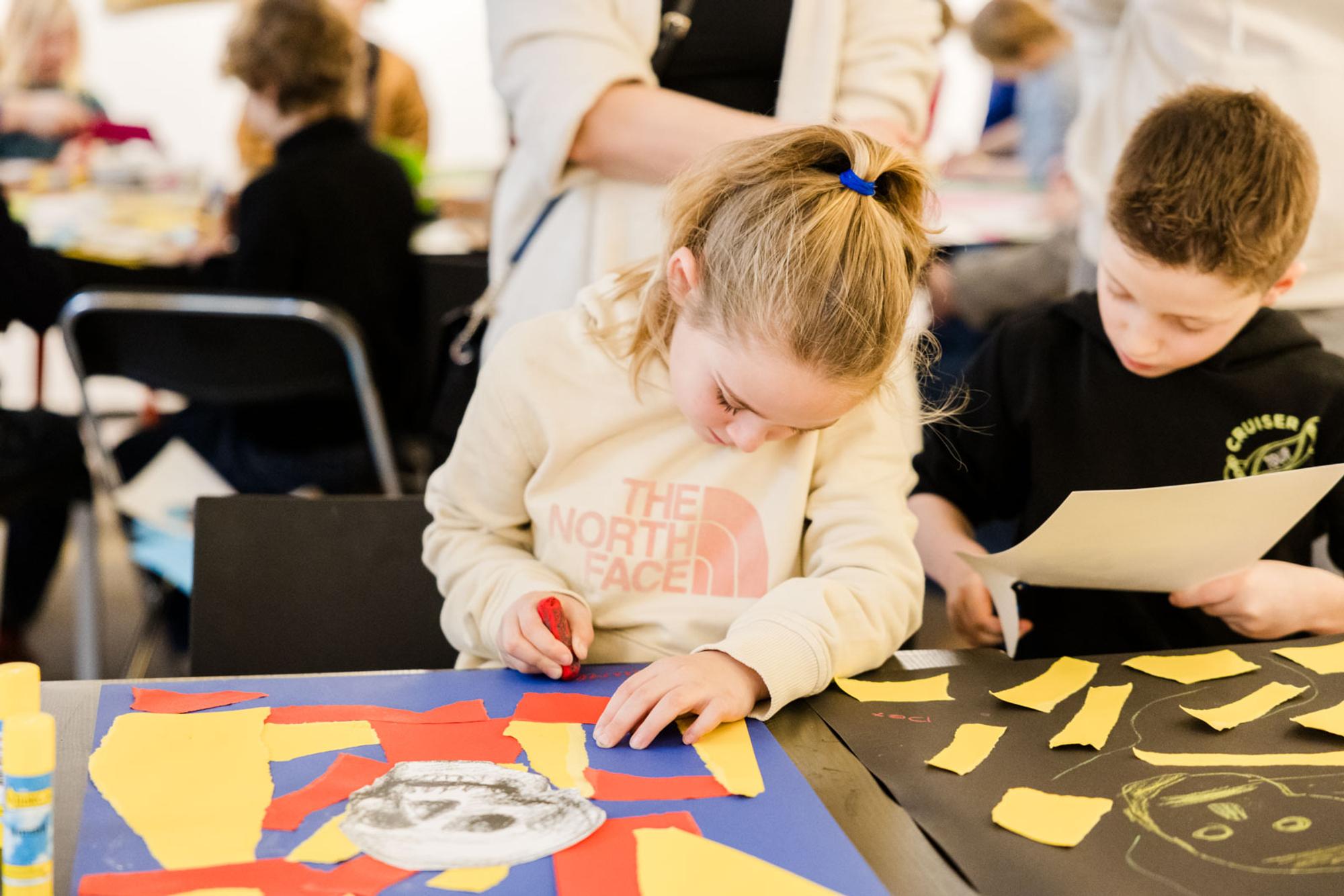 Kinderen knutselen met gekleurd papier tijdens een workshop.