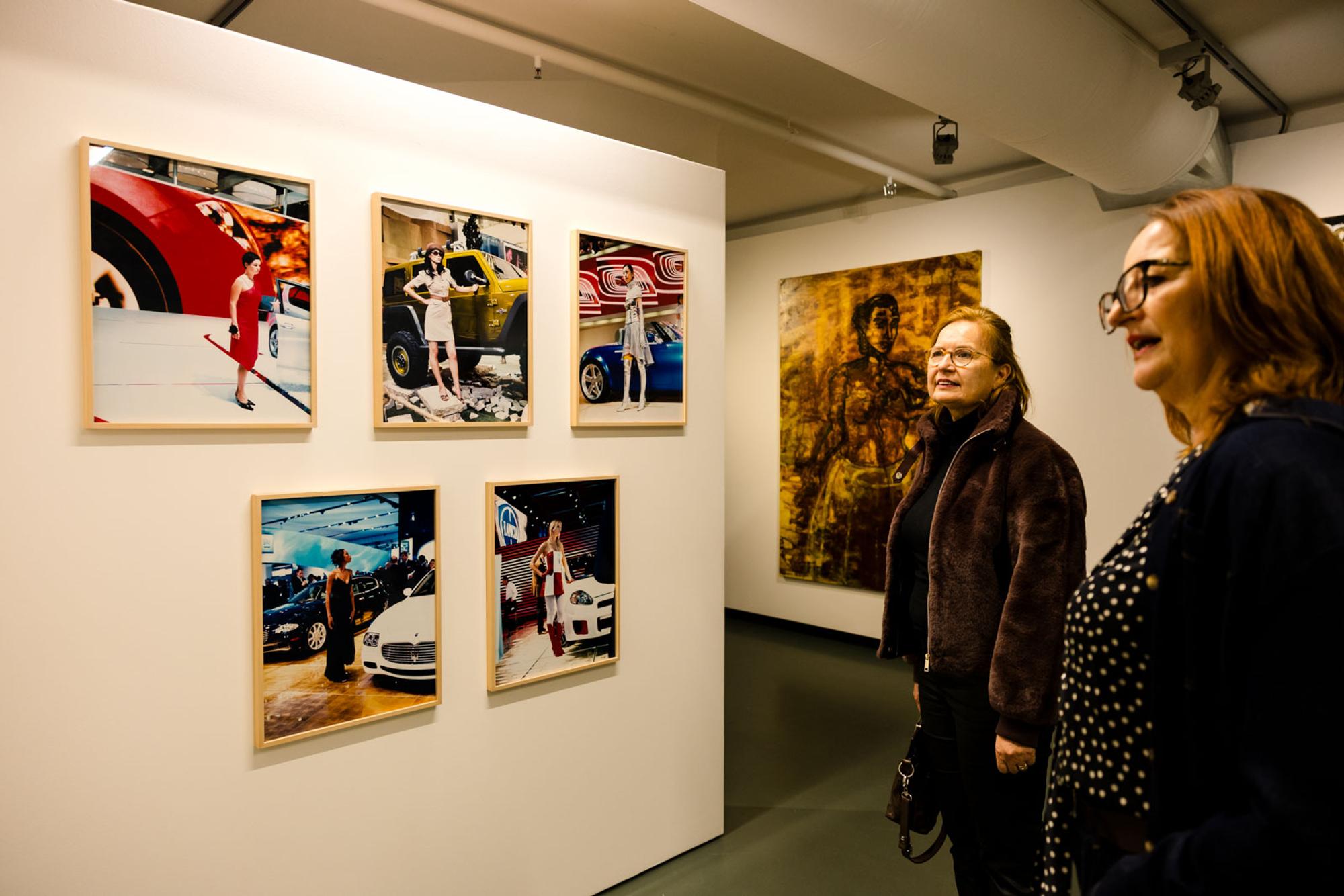Twee bezoekers bekijken fotokunst in de museumzaal van SCHUNCK, tijdens Rooted in Change