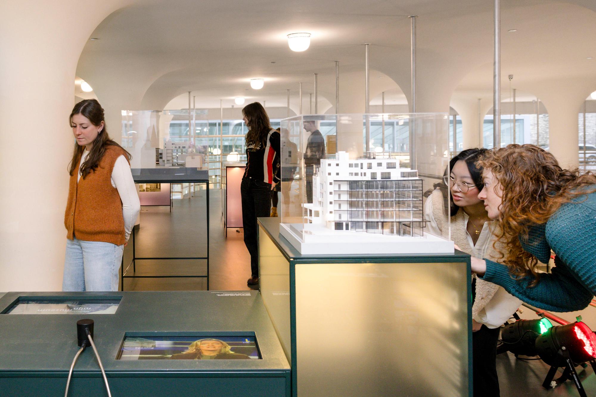 Bezoekers bekijken maquettes en interactieve presentaties in een tentoonstelling over architectuur en stadsontwikkeling in SCHUNCK.