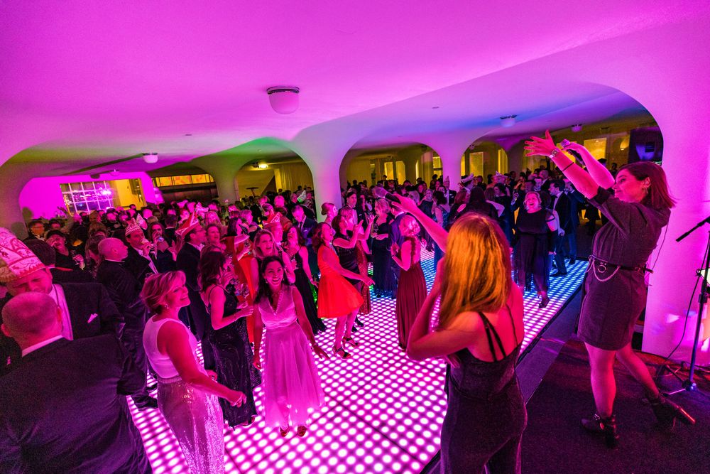 Mensen in feestkleding dansen op een lichtgevende dansvloer in het SCHUNCK Glaspaleis.