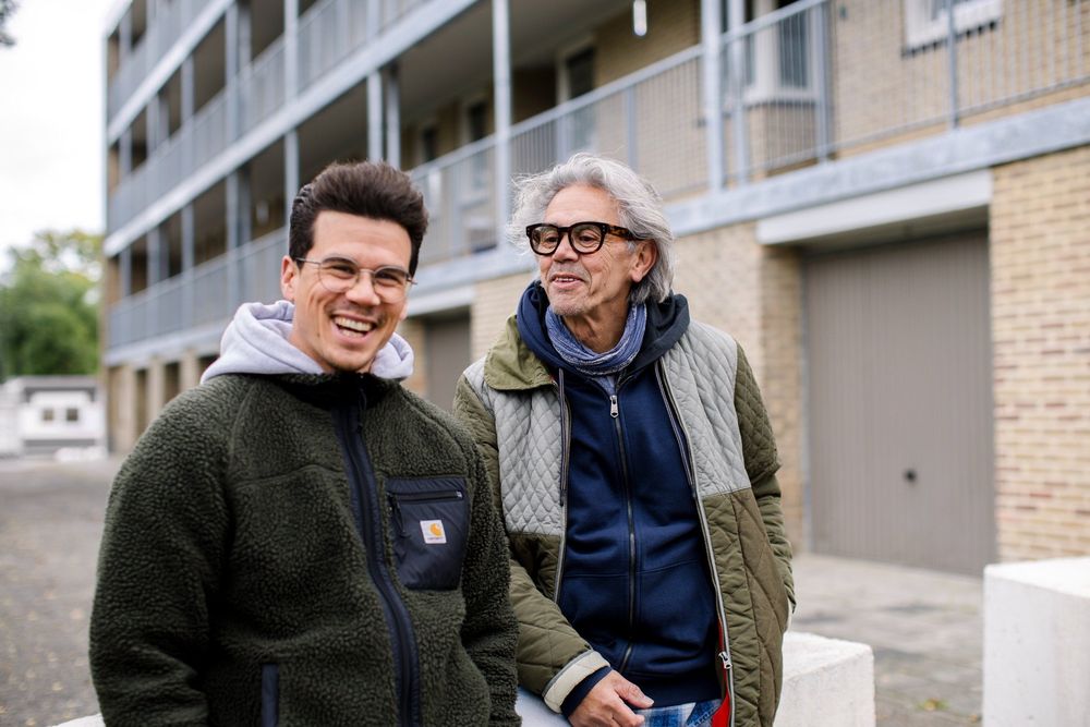 Jop Vermeesch en Emile Vermeesch samen buiten in een woonwijk, lachend in gesprek tijdens het project Kolensporen.