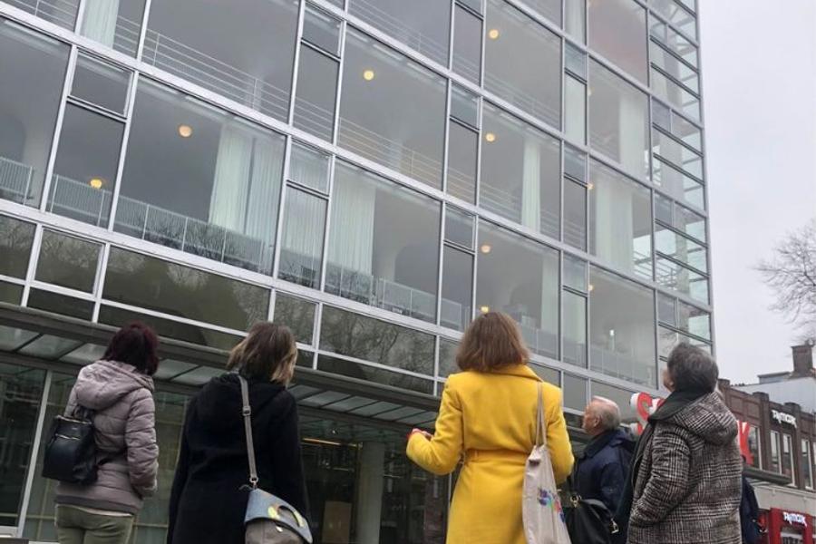 Bezoekers luisteren aandachtig tijdens een gebouwenrondleiding voor SCHUNCK Glaspaleis, met zicht op de iconische glazen gevel.