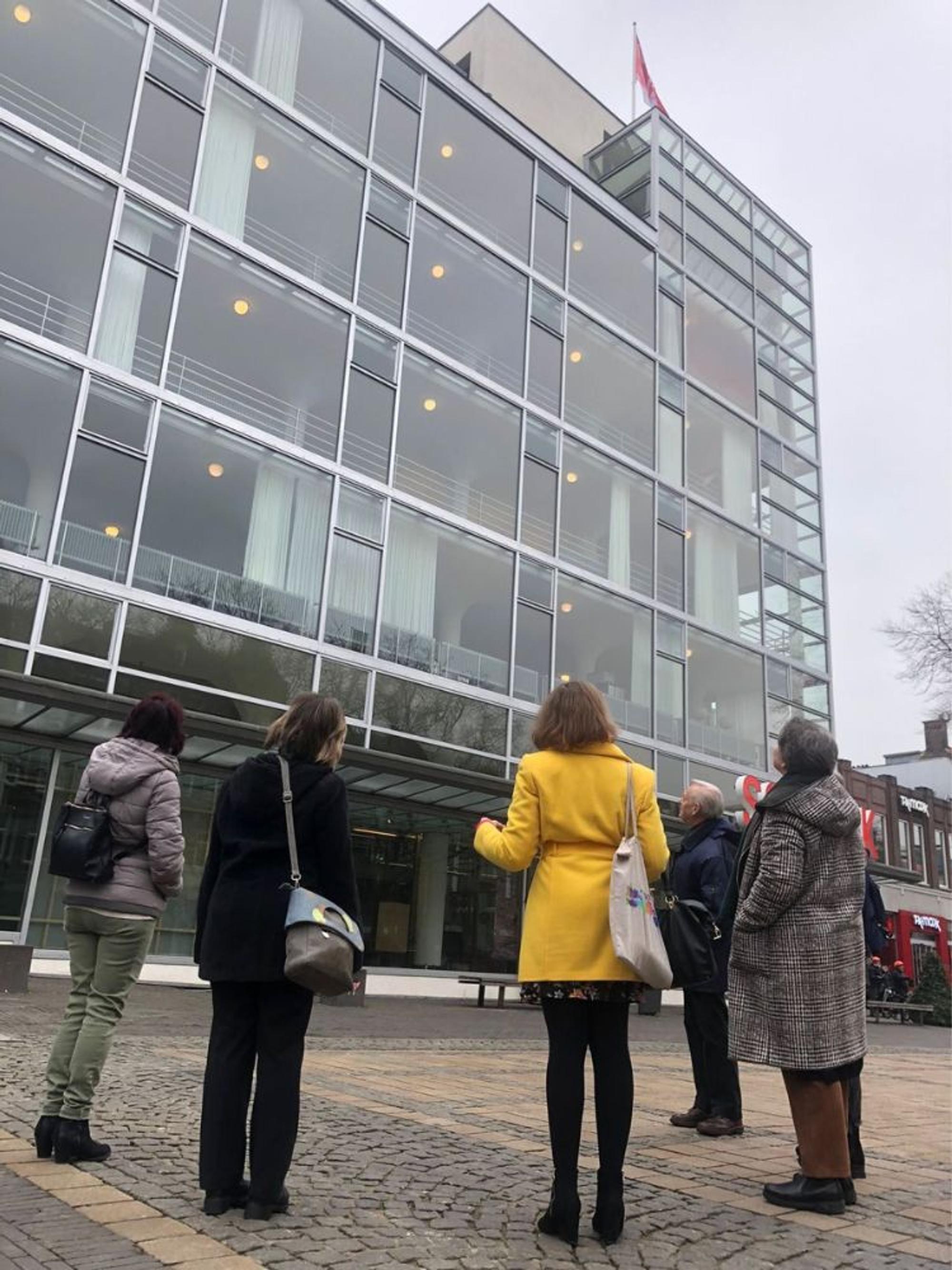 Bezoekers luisteren aandachtig tijdens een gebouwenrondleiding voor SCHUNCK Glaspaleis, met zicht op de iconische glazen gevel.