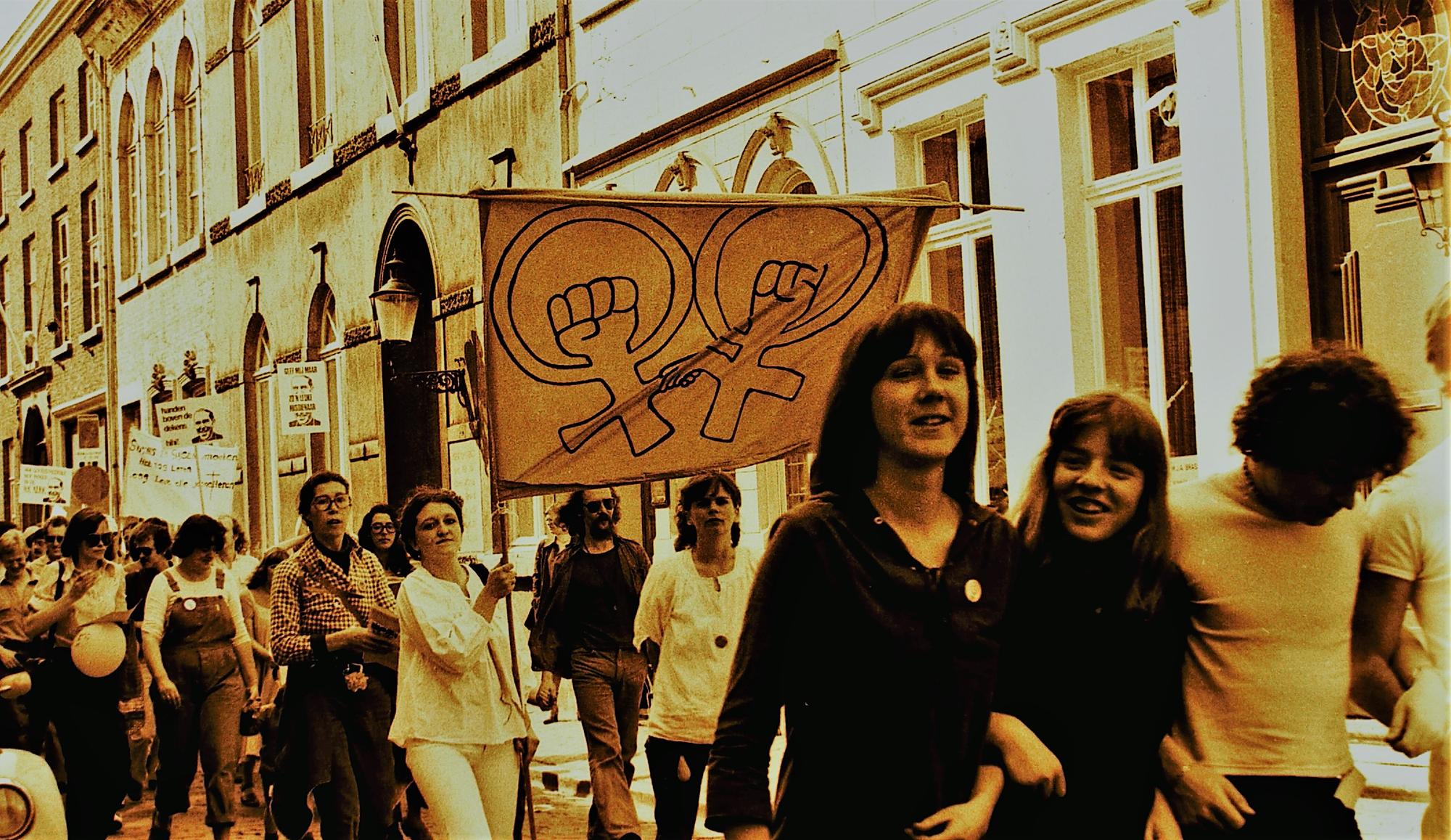 Mars tijdens Roze Zaterdag met deelnemers die een spandoek met vrouwensymbolen dragen in de stad.