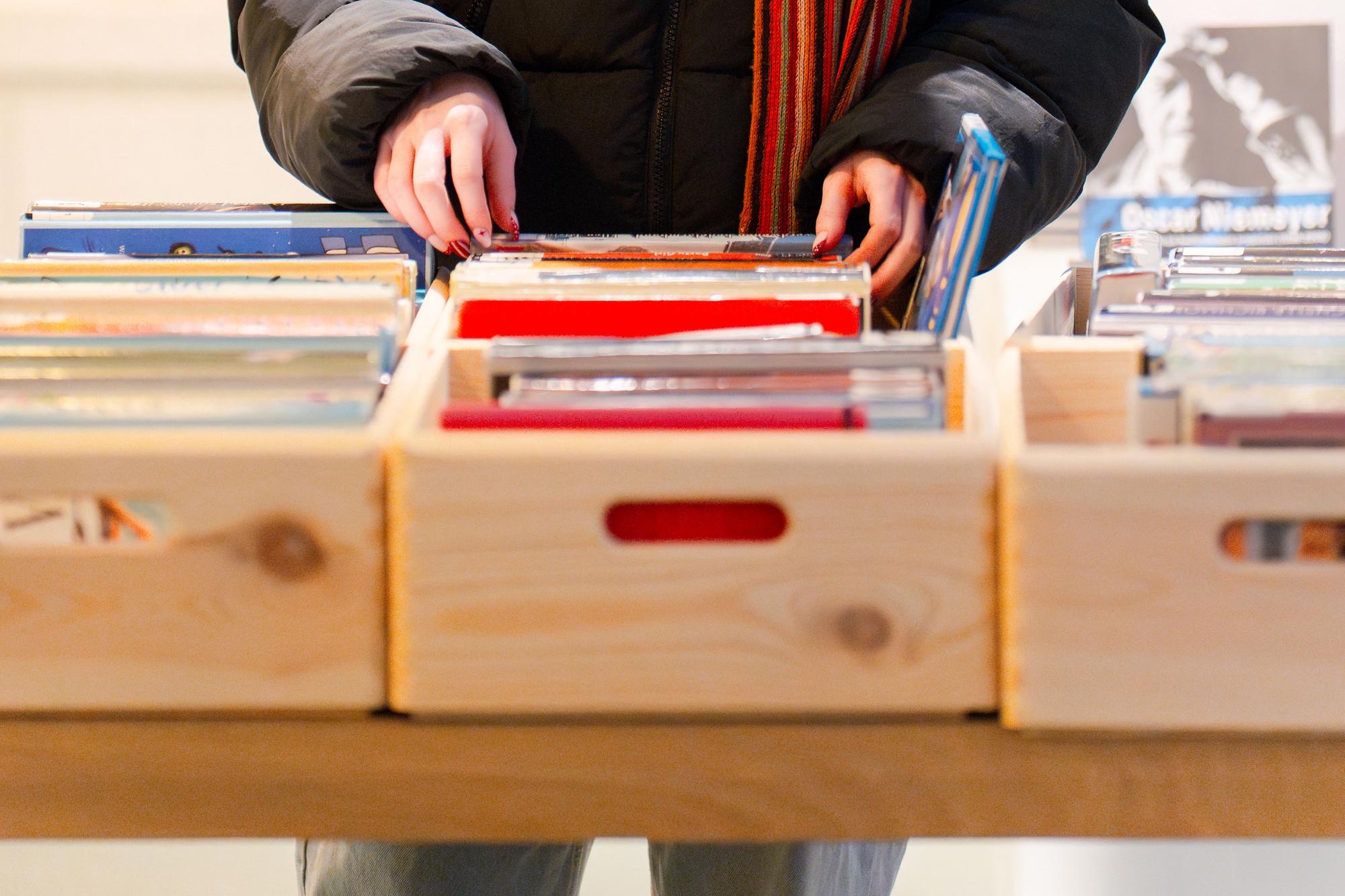 Persoon bladert door bakken met afgeschreven bibliotheekboeken.