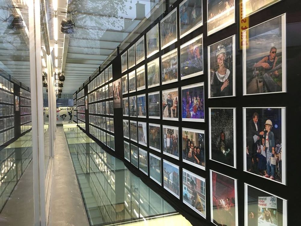 Binnenzicht in de vitrine van SCHUNCK met twee lange wanden vol ingelijste foto's, onderdeel van de installatie ‘The Future is Mine’, die diverse momenten en mensen uit de mijnstreek in beeld brengt.