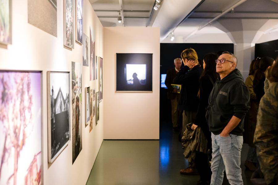 Bezoeker bekijkt schilderijen en foto's aan de wand van de museumzaal van SCHUNCK
