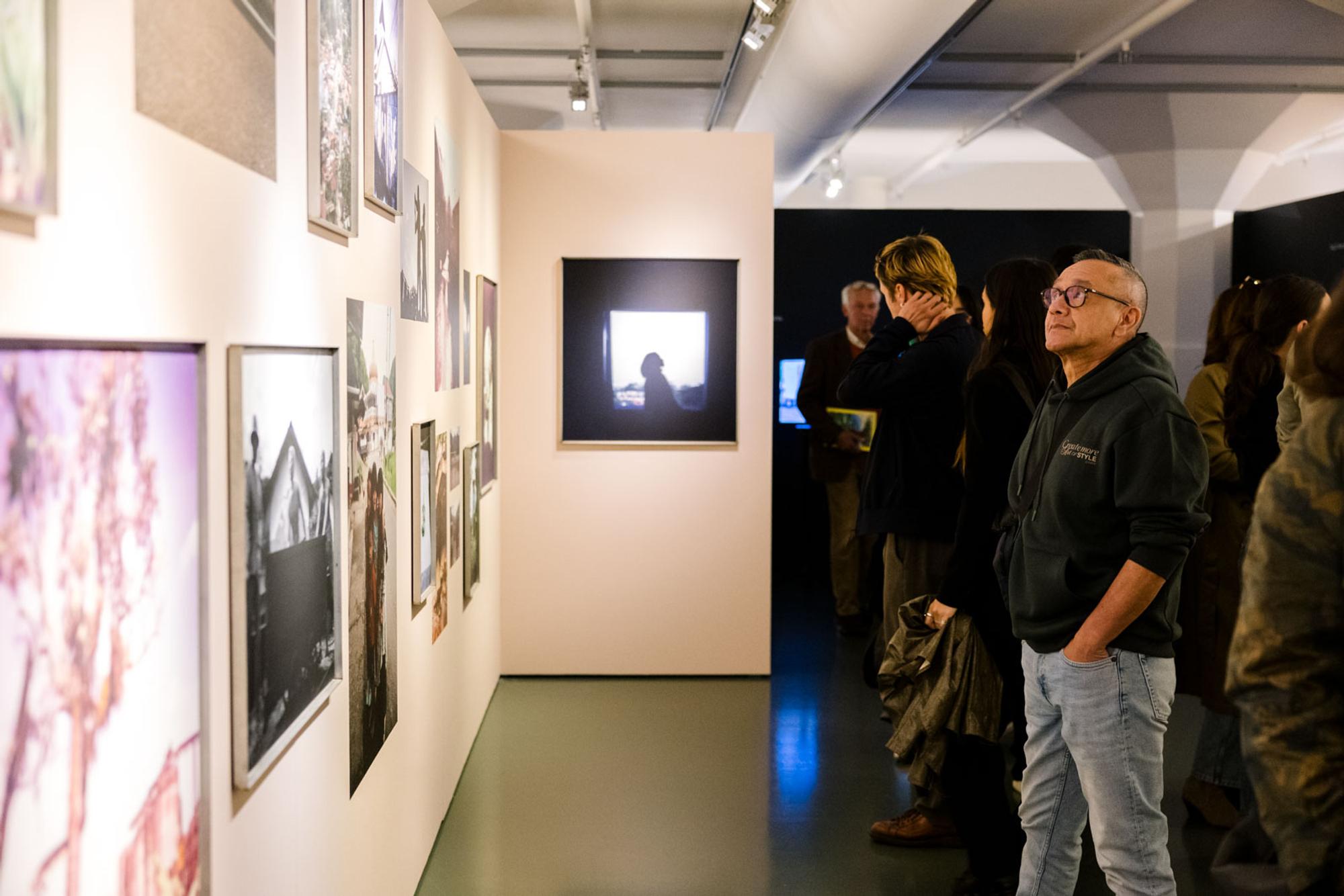 Bezoeker bekijkt schilderijen en foto's aan de wand van de museumzaal van SCHUNCK