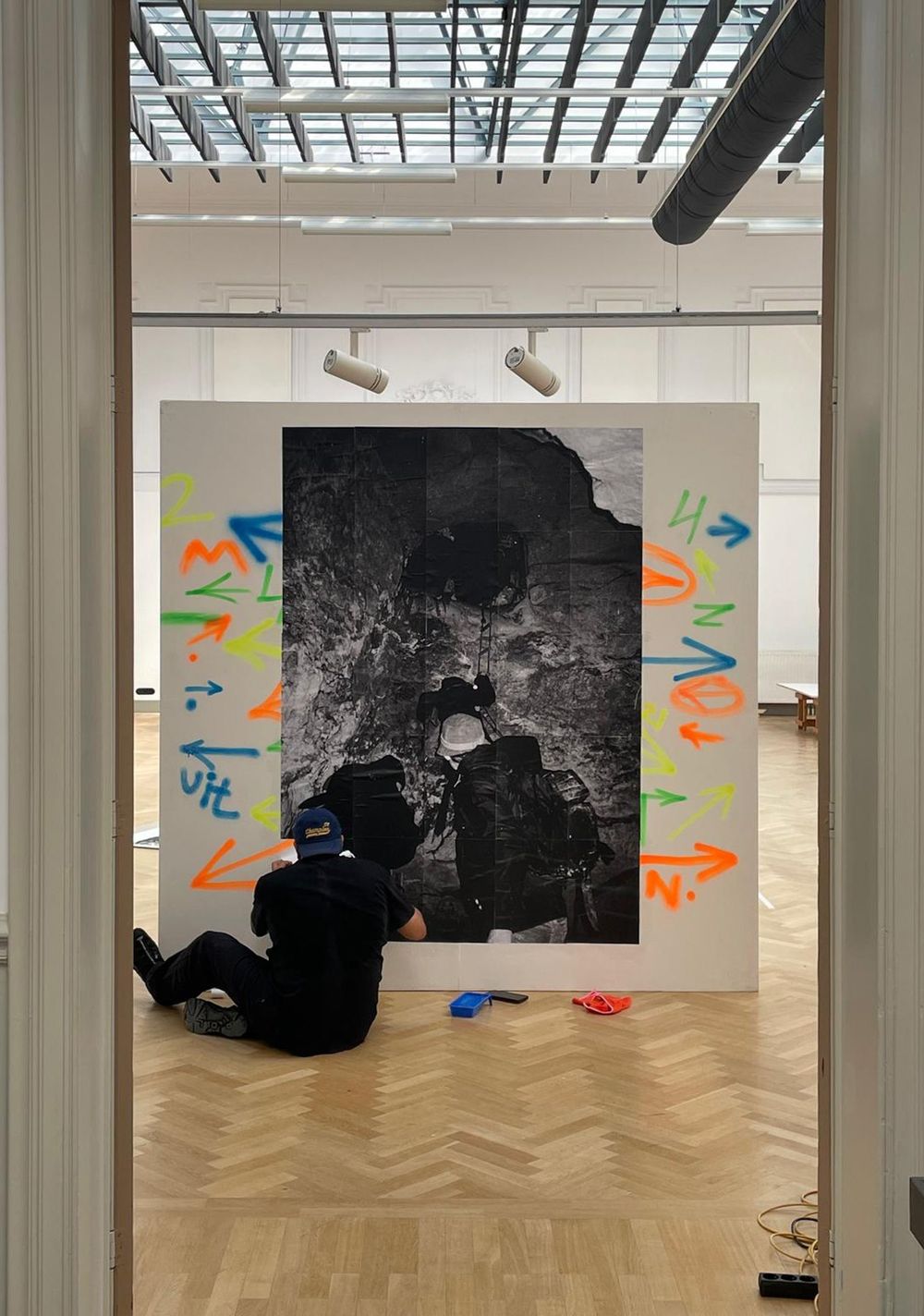 Een persoon werkt aan de opbouw van een presentatie met een grote zwart-witfoto, omringd door kleurrijke pijlen en tekens.