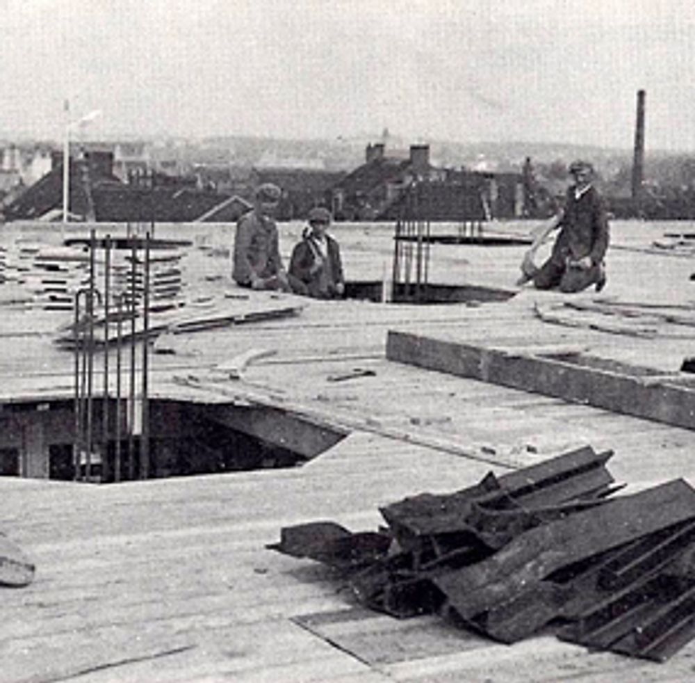 Werknemers aan het werk op het dak van het Schunck-gebouw tijdens een verbouwing.