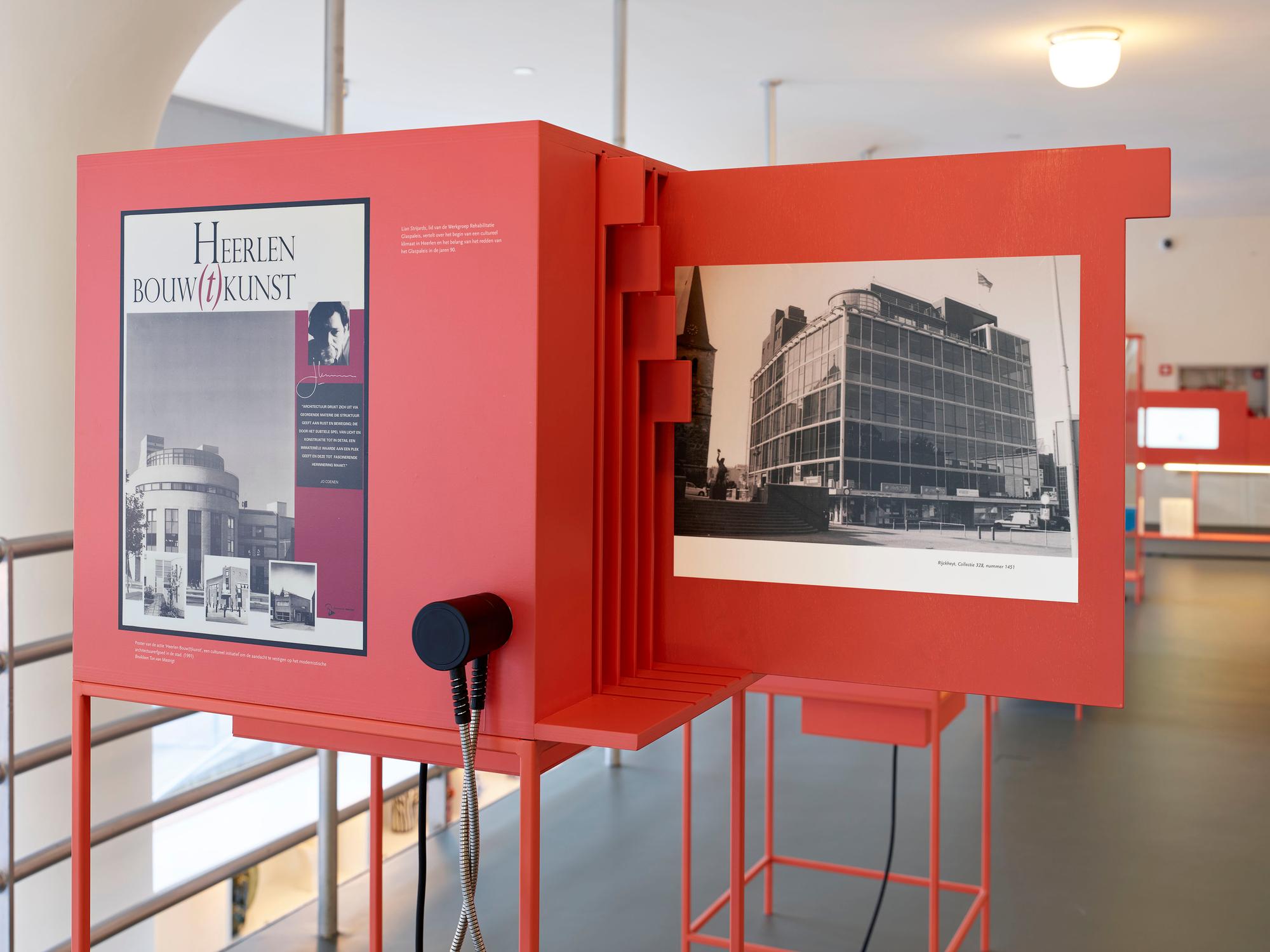 Interactieve rode tentoonstellingskast in SCHUNCK Glaspaleis, met historische foto's en informatie over de bouwkunst in Heerlen; op de opengeklapte zijde een zwart-witfoto van het Glaspaleis uit 1937.