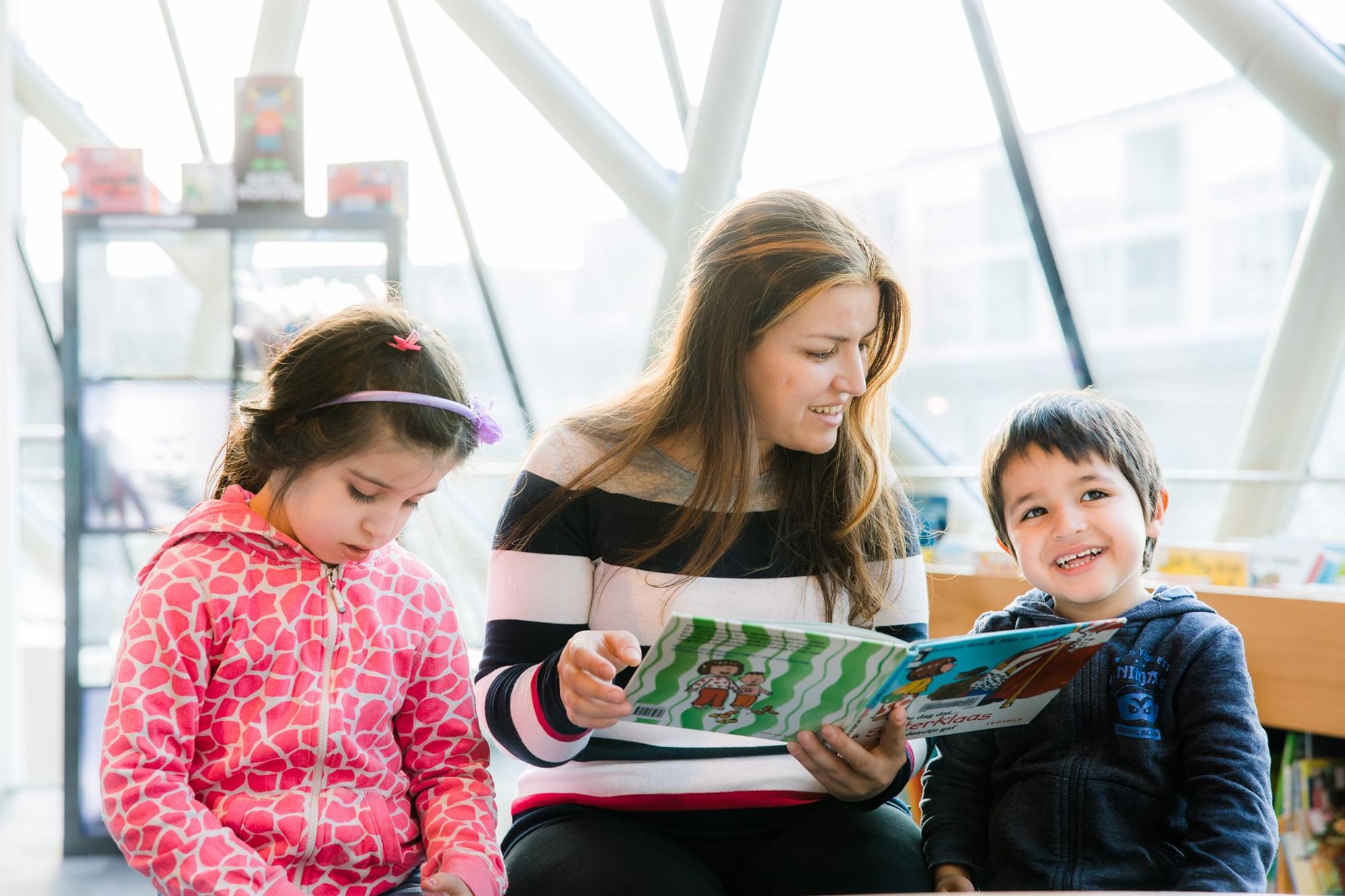 Vrouw leest voor aan twee kinderen. 
