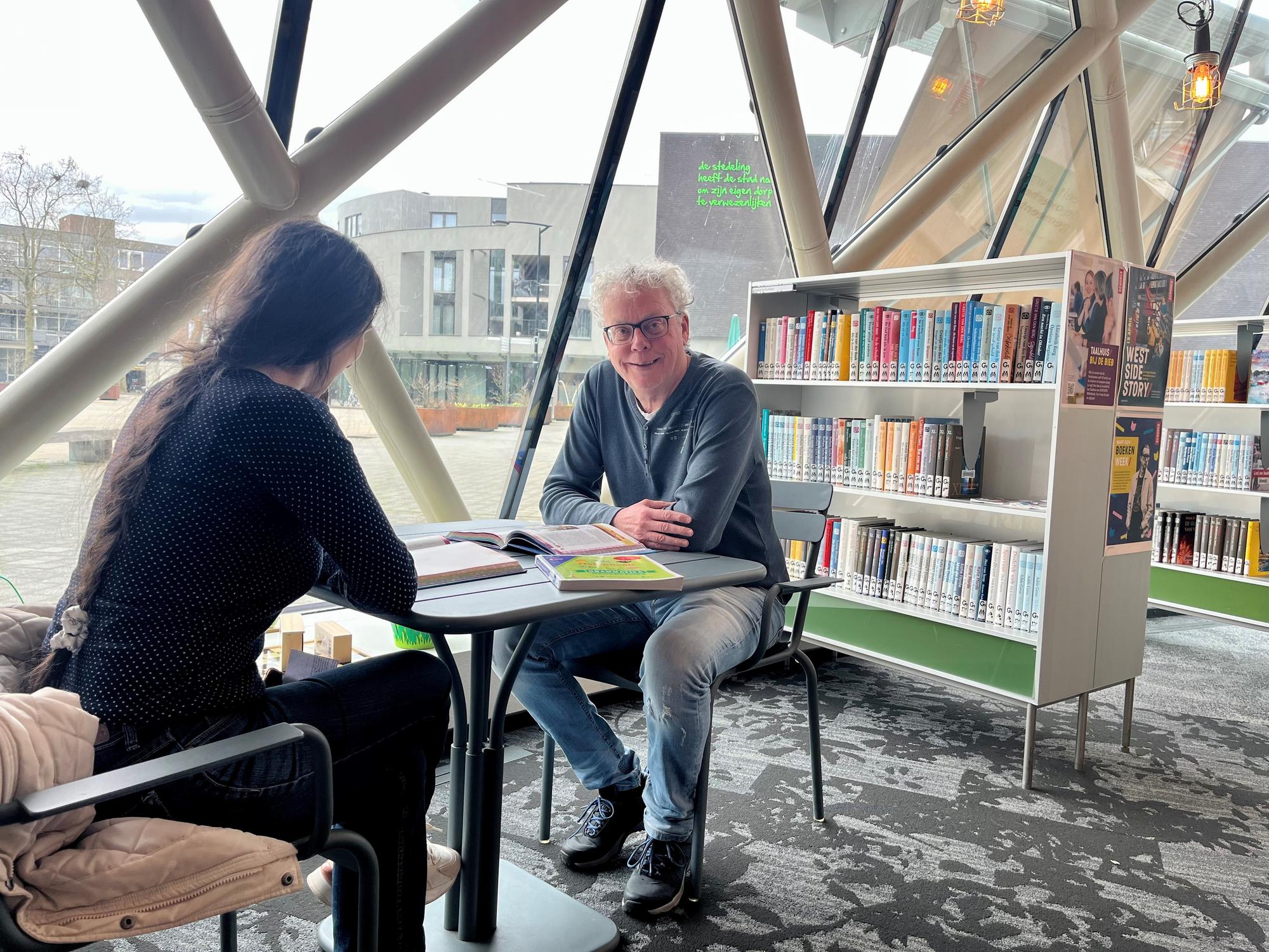 Vrijwilliger Ger Hanno zit aan tafel met boek. 