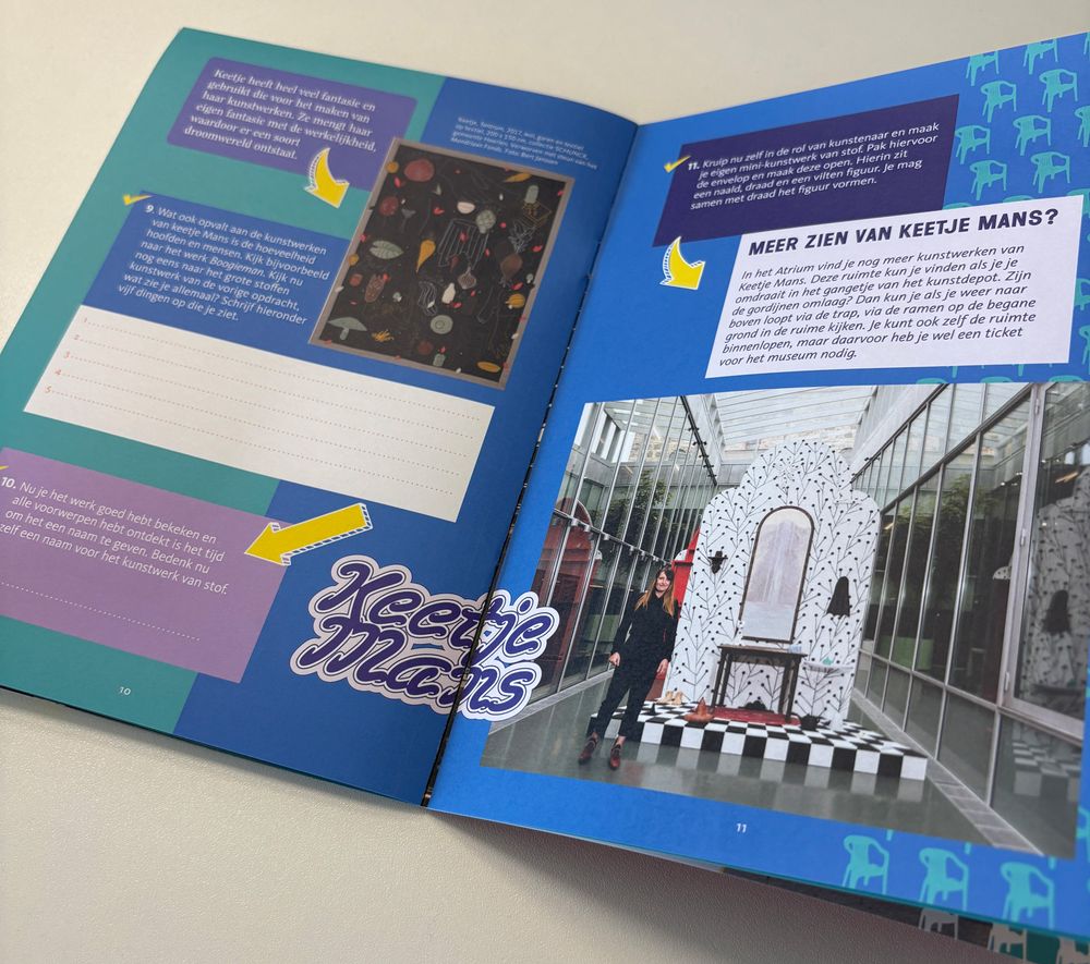 Open boek met kleurrijke pagina’s. Links staat een schilderij met Nederlandse tekst en ruimte voor notities over het kunstwerk. Rechts een foto van een kunstinstallatie in een glazen gebouw, met informatie over kunstenaar Keetje Mans.