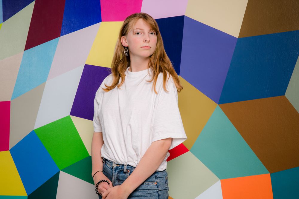 Portret van een jonge vrouw voor een kleurrijke muurschildering.