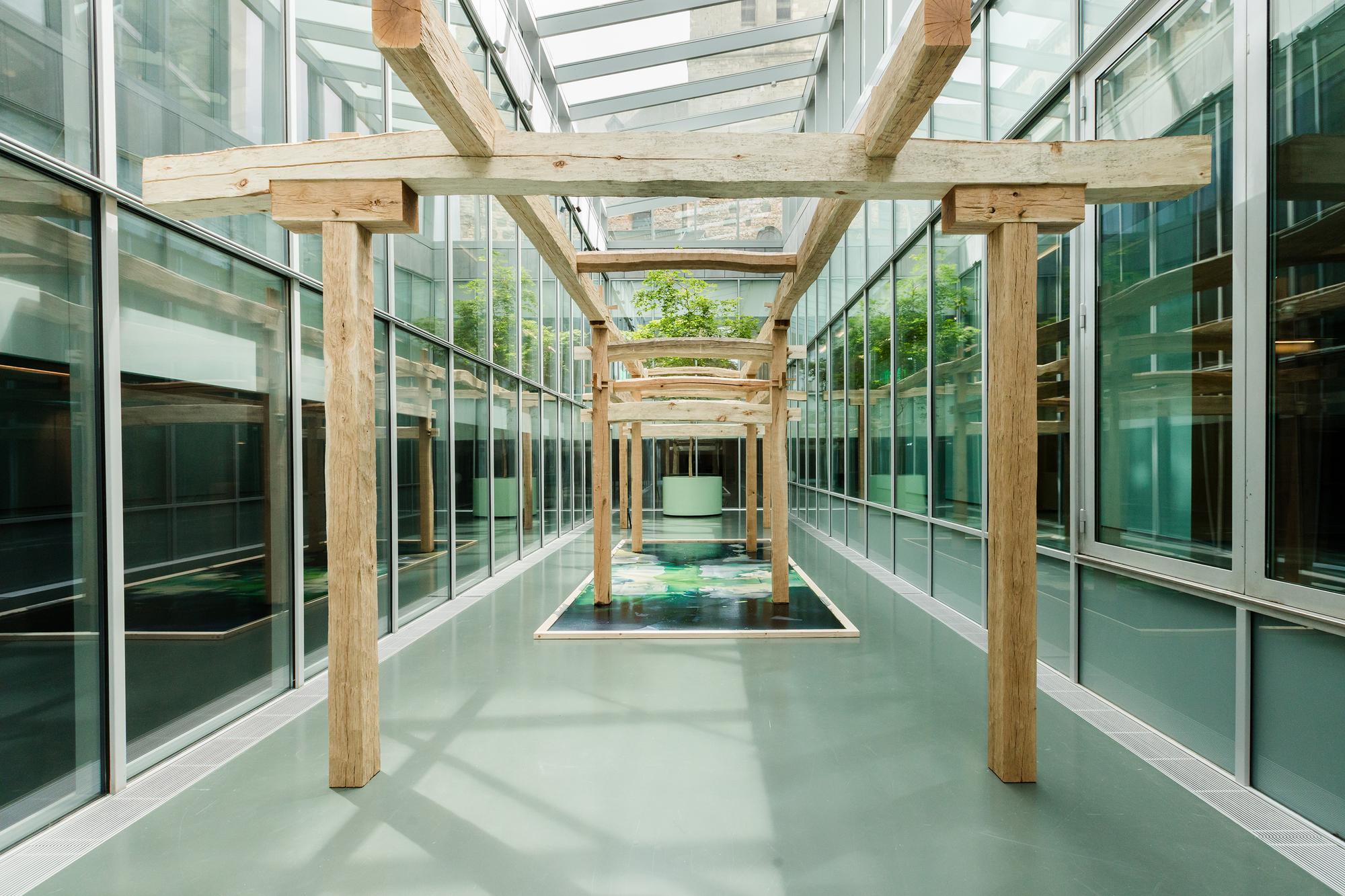 Een installatie met houten constructies en een groot werk op de vloer in de glazen binnenruimte van SCHUNCK.