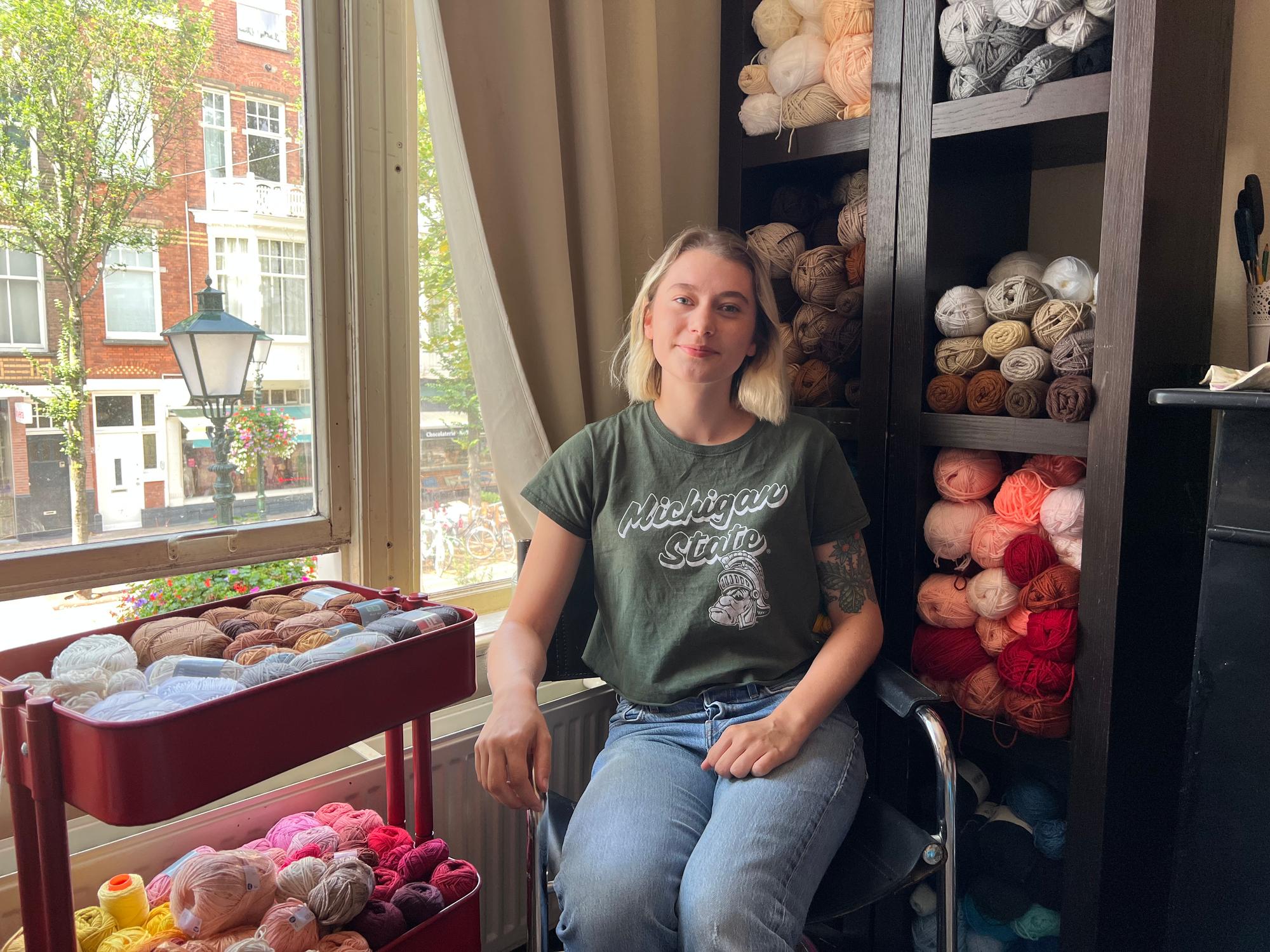 Portret van Quinn Zeljak in haar atelier tussen kastjes met bollen wol.