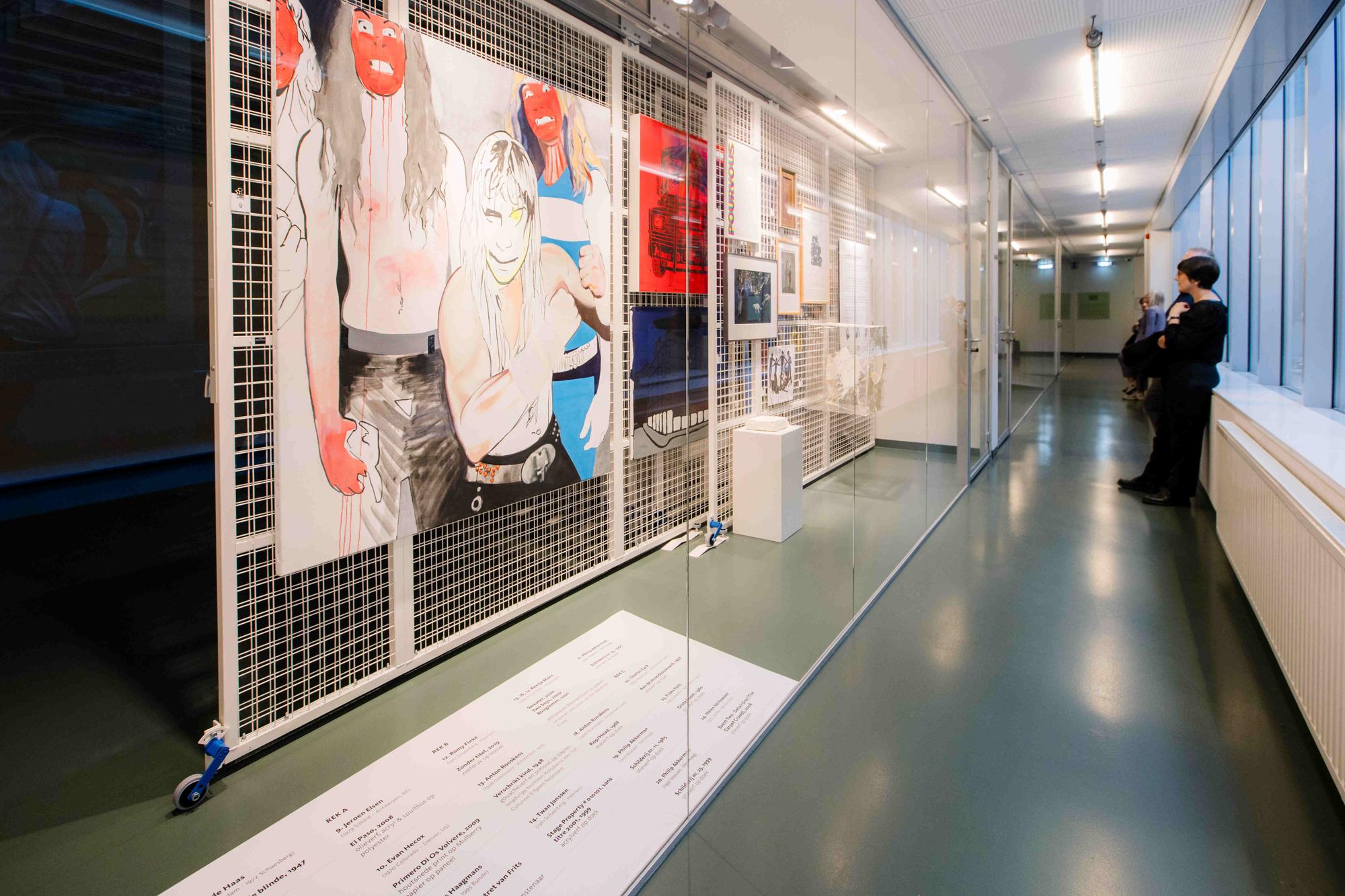 Een foto van het kunstdepot in SCHUNCK Glaspaleis Heerlen waarbij een paar bezoekers kijken naar verschillende kunstwerken die gepresenteerd worden op hekken. 