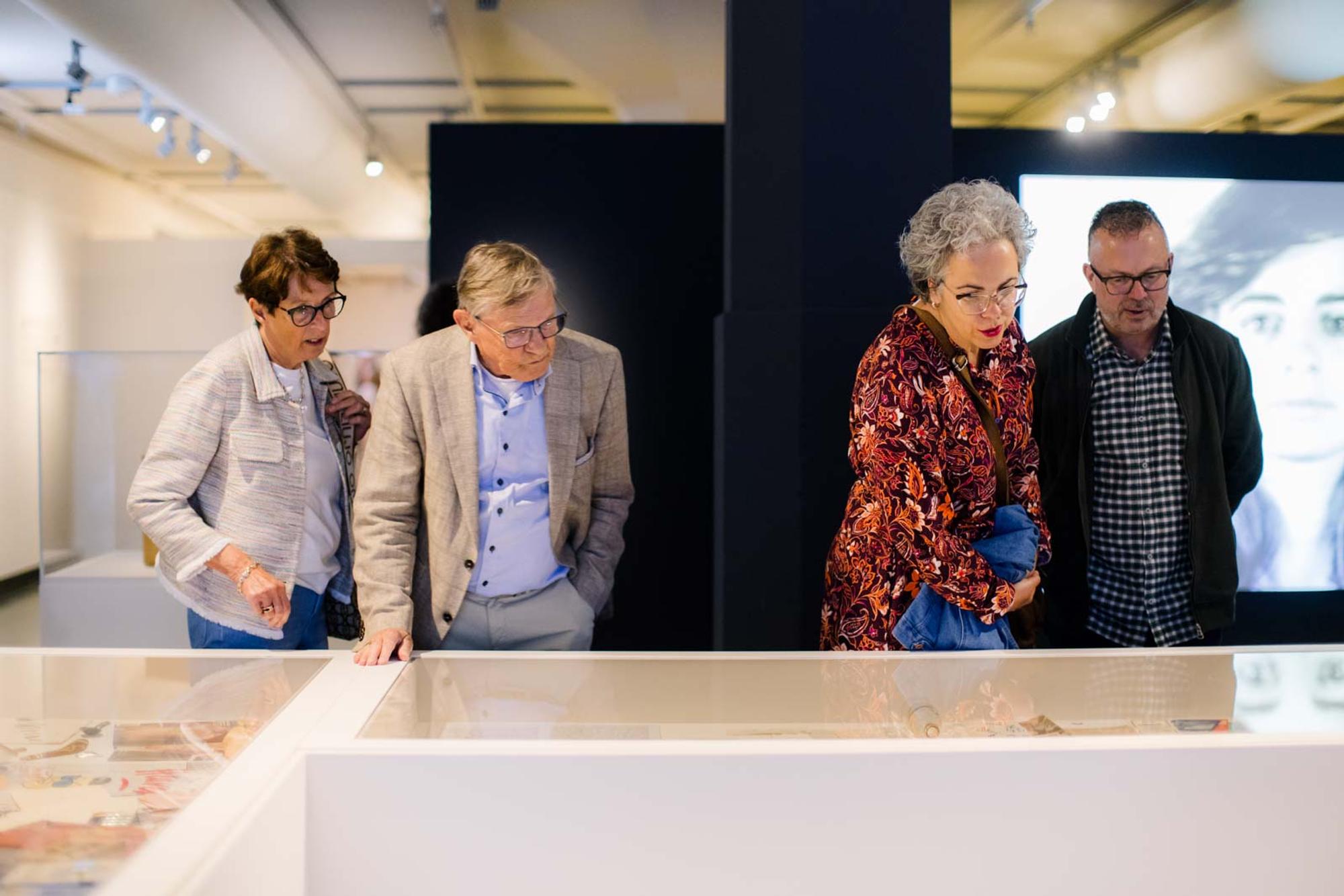 Bezoekers kijken in vitrine tijdens opening expositie Andy Warhol Vanitas. 