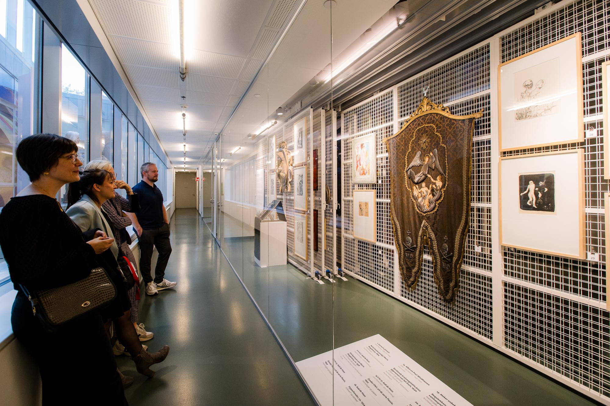 Bezoekers kijken naar kunstwerken aan het bewegende rek in het Kunstdepot. 