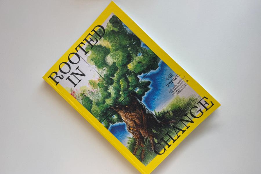 Een felgele publicatie met op de omslag een werk van een grote boom met groene bladeren en diepe wortels tegen een blauwe lucht. Op de voorkant staat in zwarte letters de titel Rooted in Change.